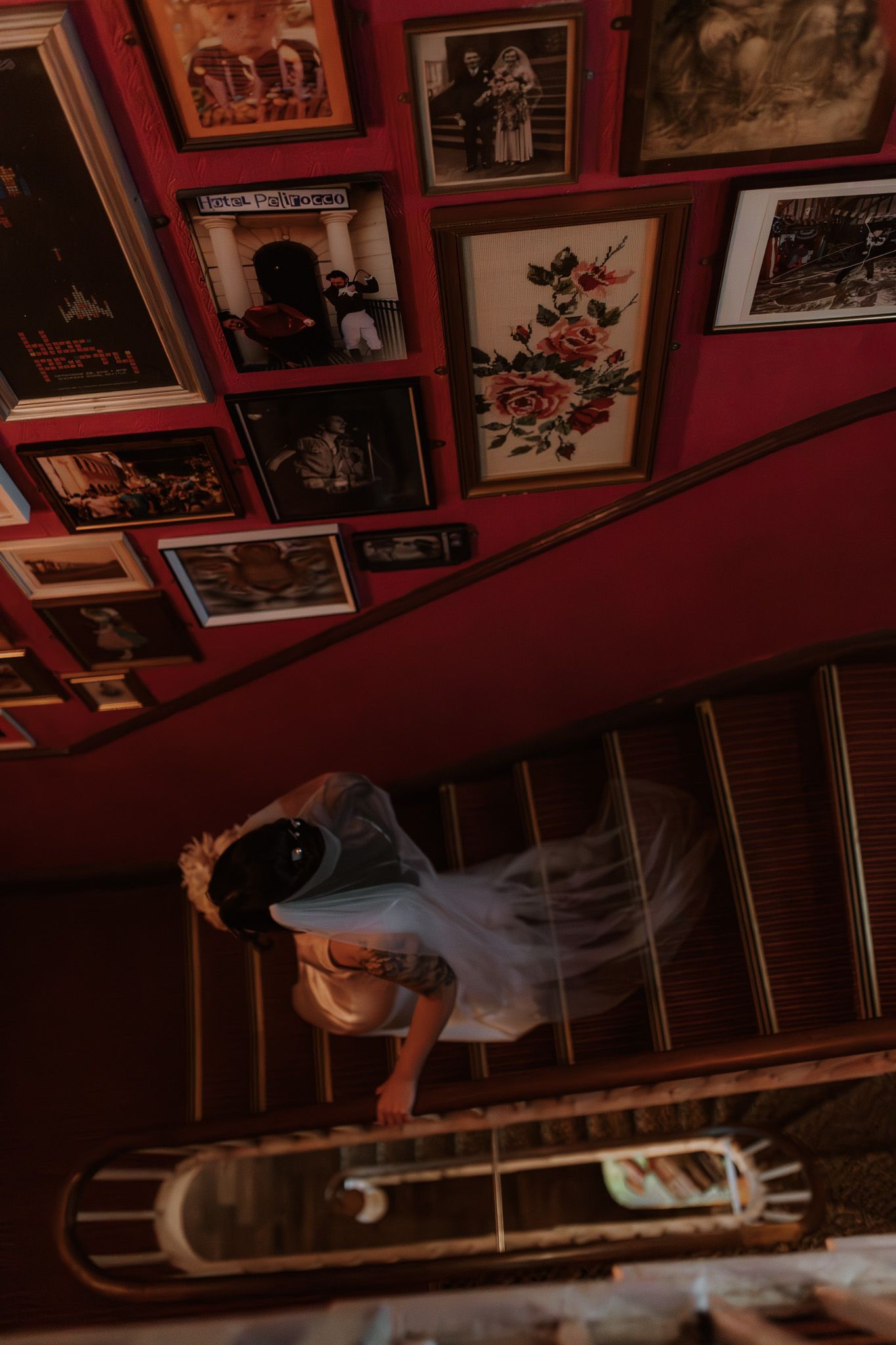 Artistic overhead view of wedding preparations through ornate staircase with red walls.
