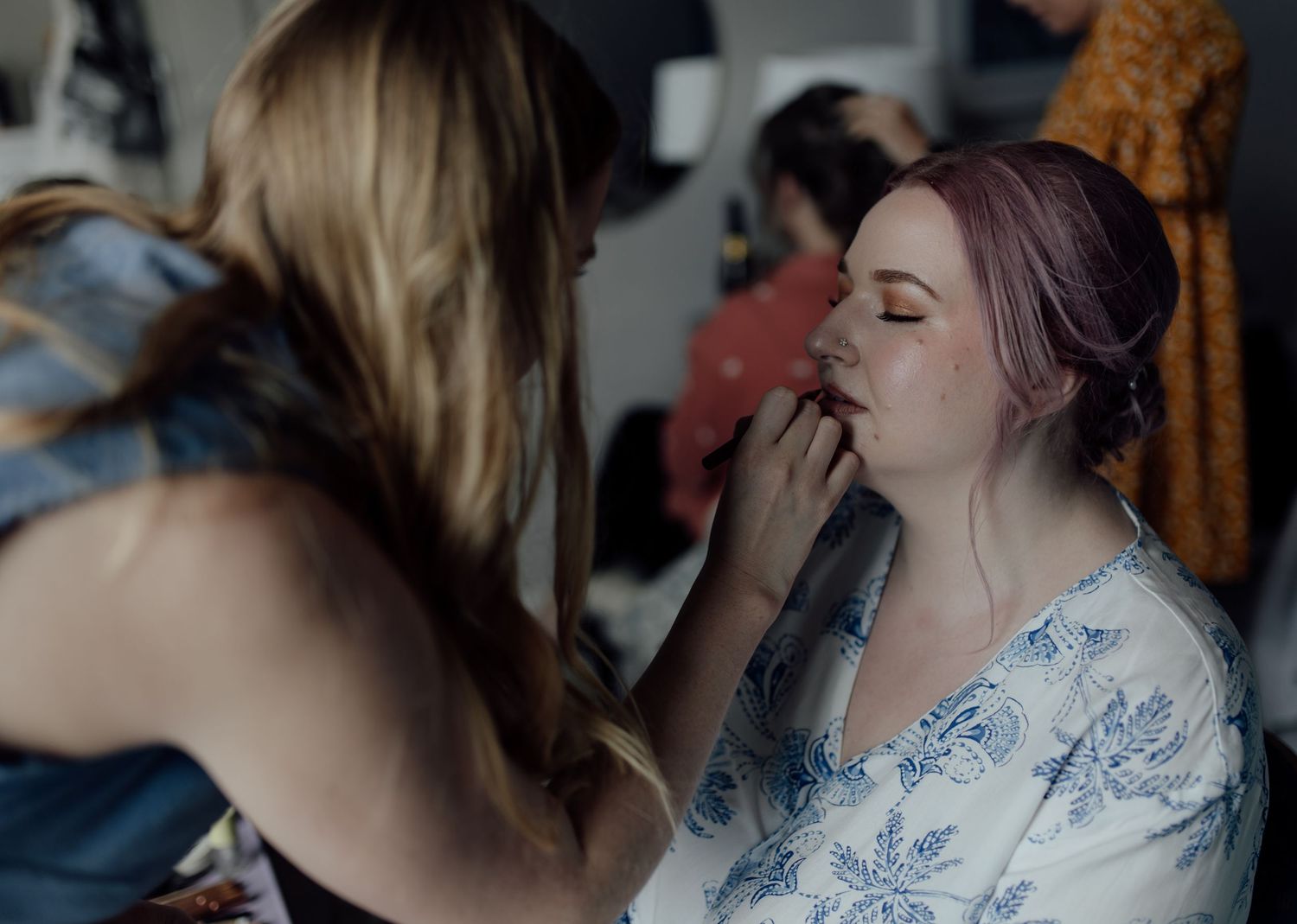 A sequence of photos showing someone applying make up to a bride.