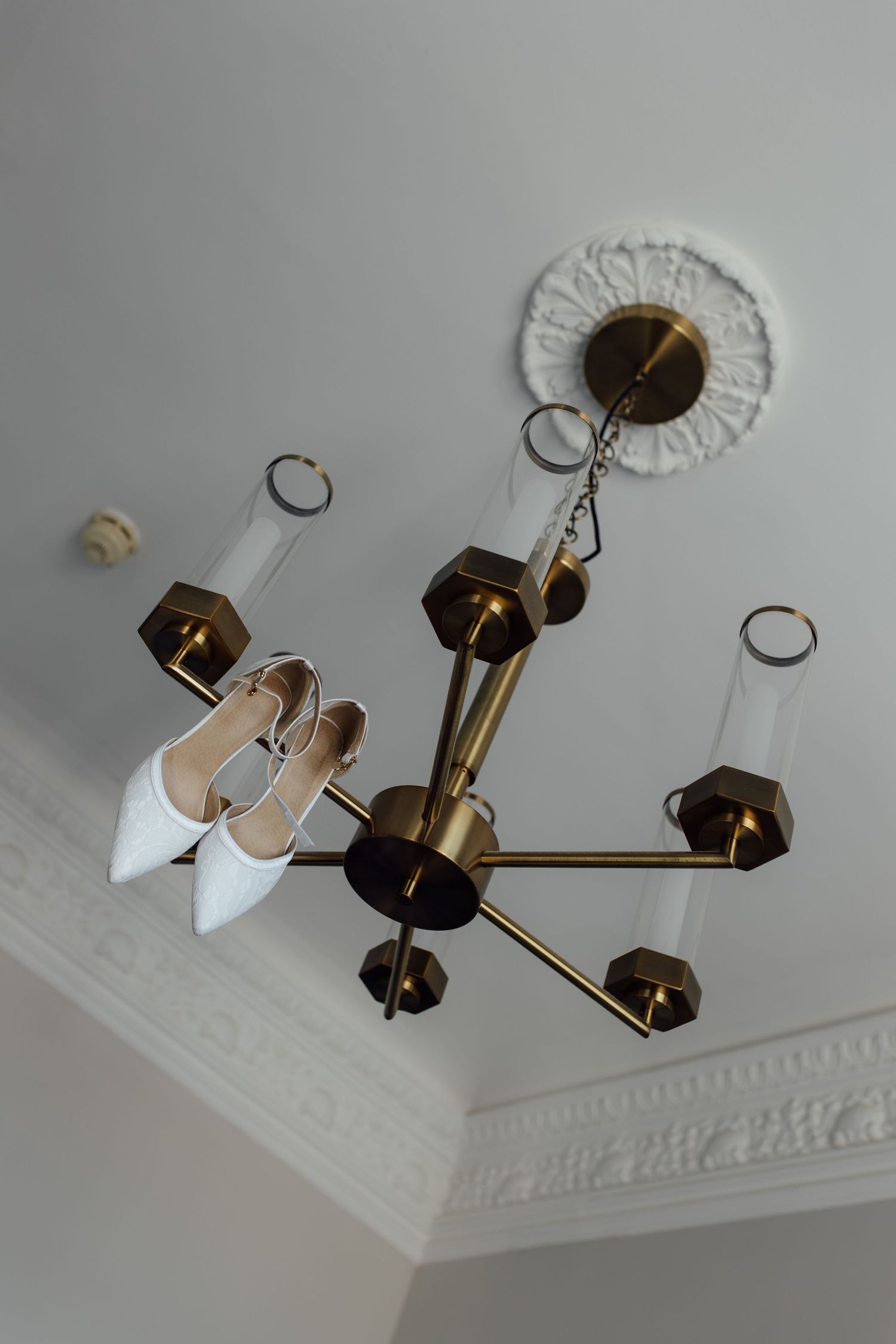 A series of photos showing the installation process of a modern geometric brass ceiling light fixture with white accents.