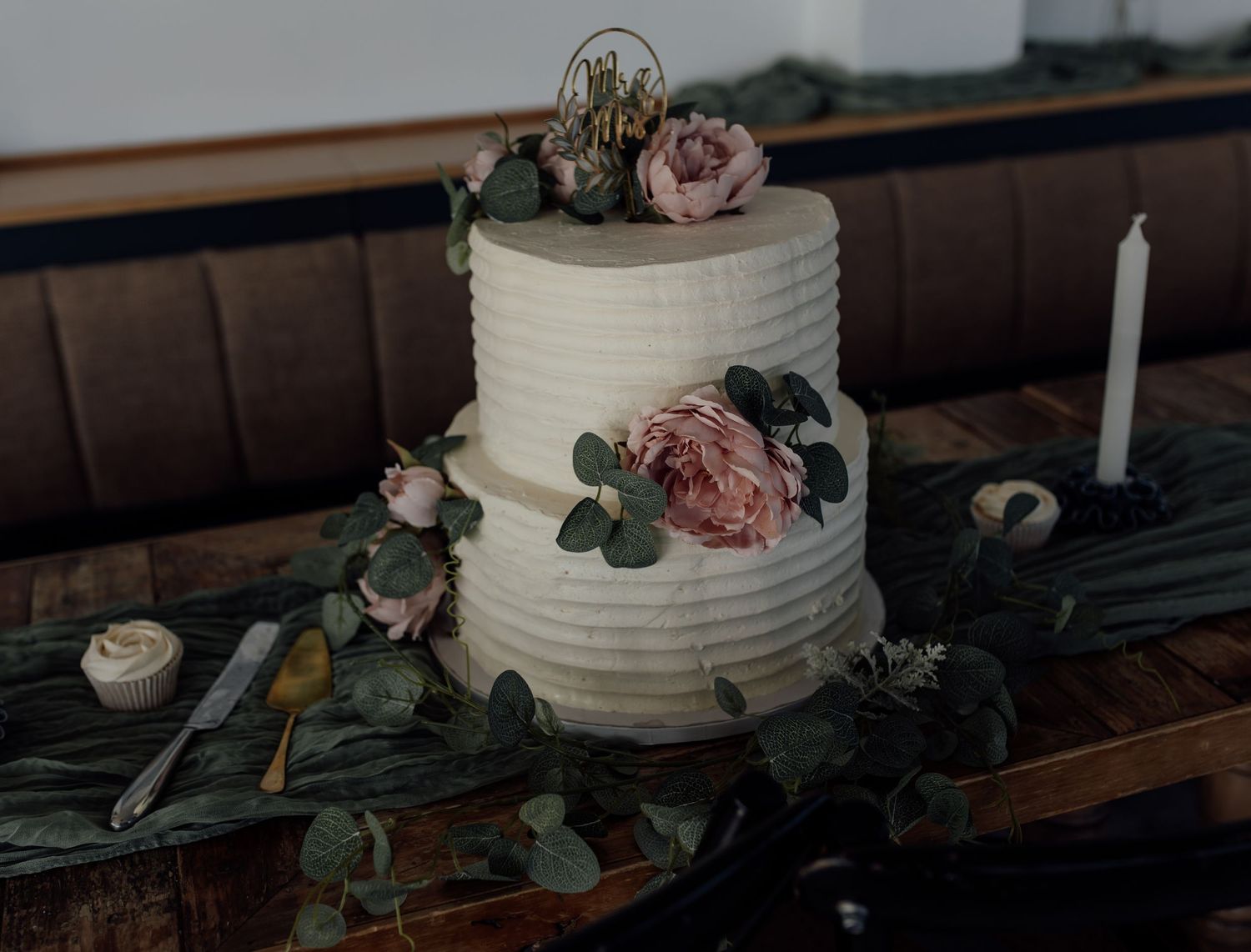 A collection of romantic wedding cake images with blush pink roses and eucalyptus decorations on wooden tables.