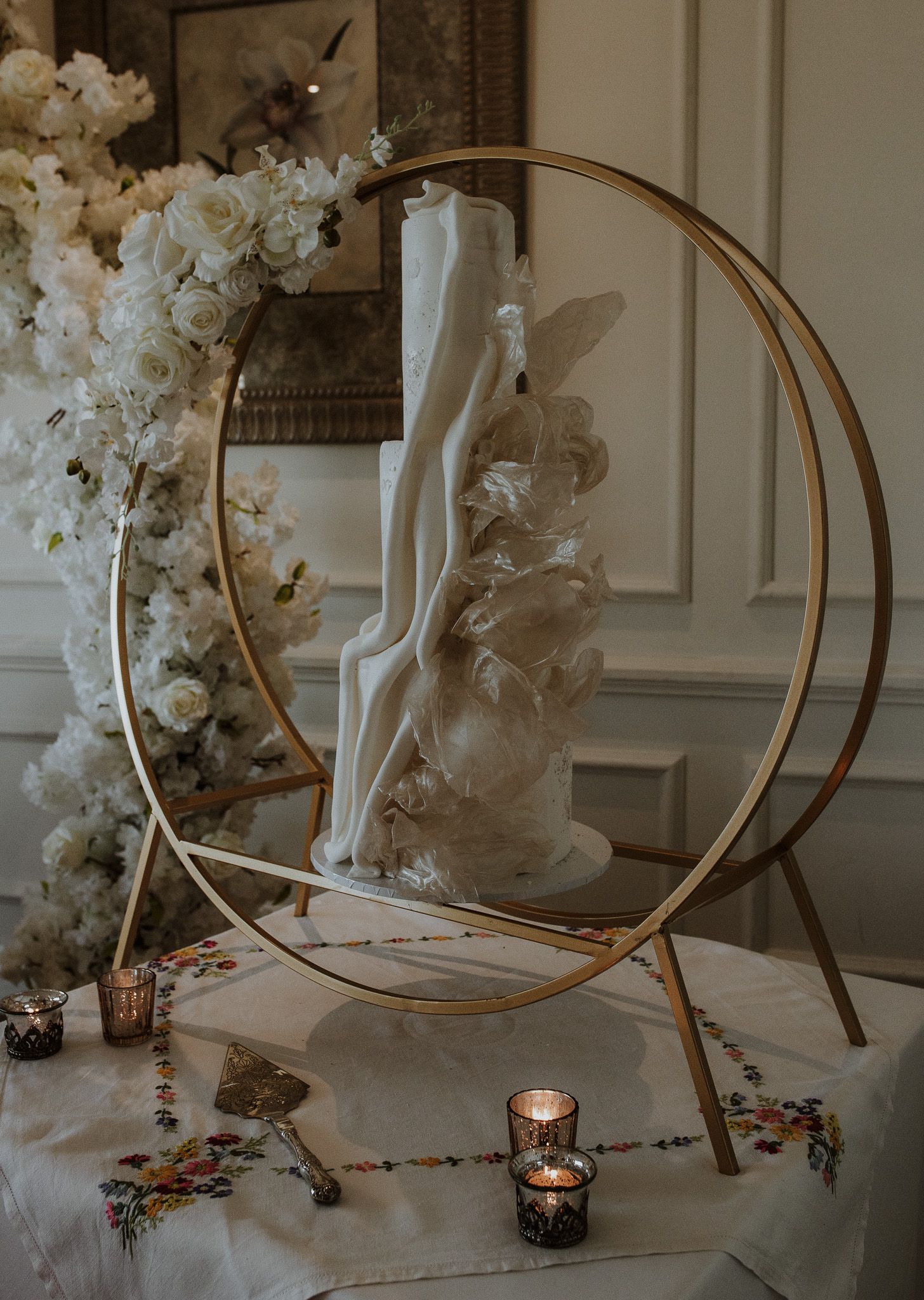 Elegant gold hoop decorations with candles and white floral arrangements create a romantic wedding backdrop.