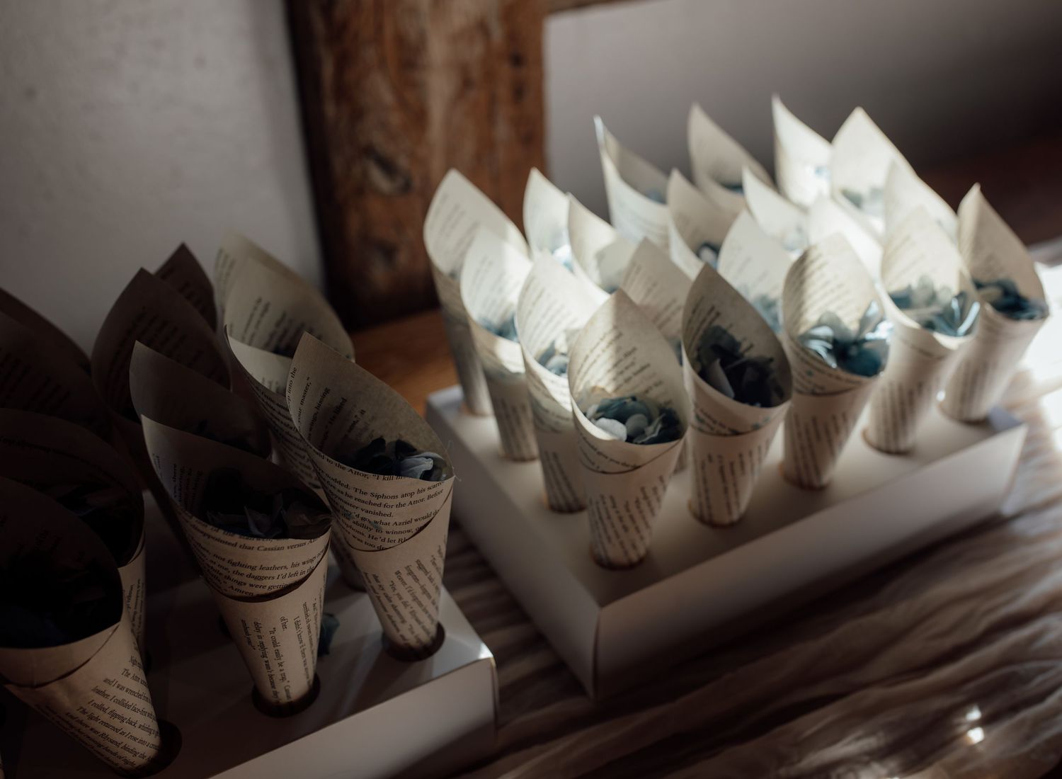 Row of small paper cones with black and white tissue paper decorations arranged in a line on a dark surface.