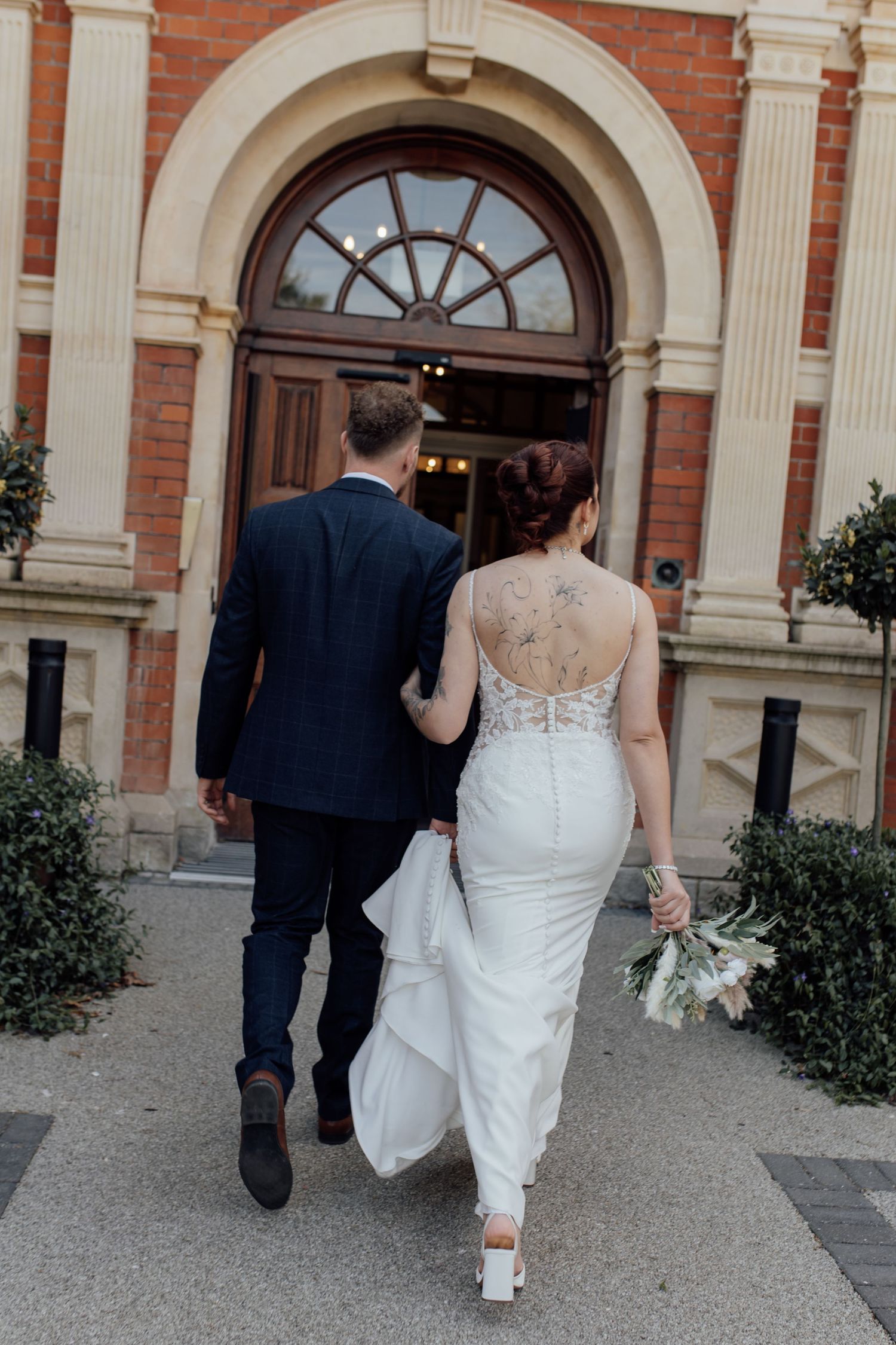 Bride and groom walk into building.