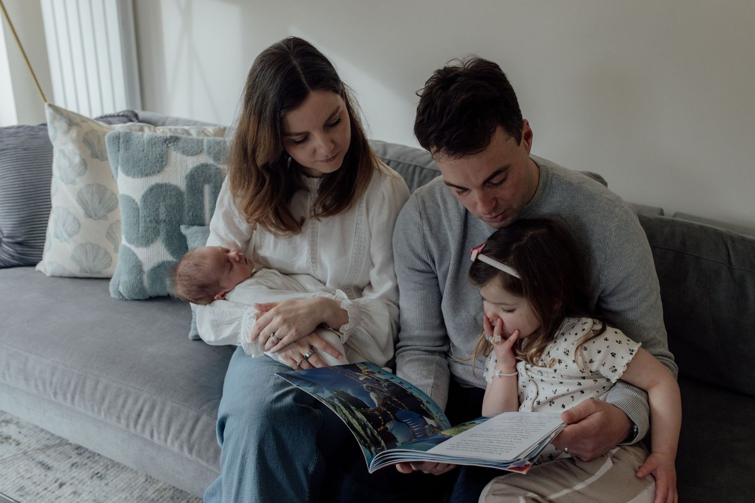 Family members sitting together on a couch reading books and enjoying quality time at home.