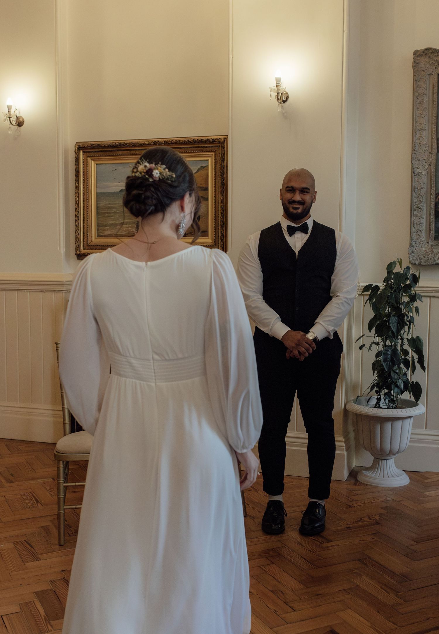 A sequence of wedding ceremony photos showing a couple in formal attire on a hardwood floor with elegant wall decor.