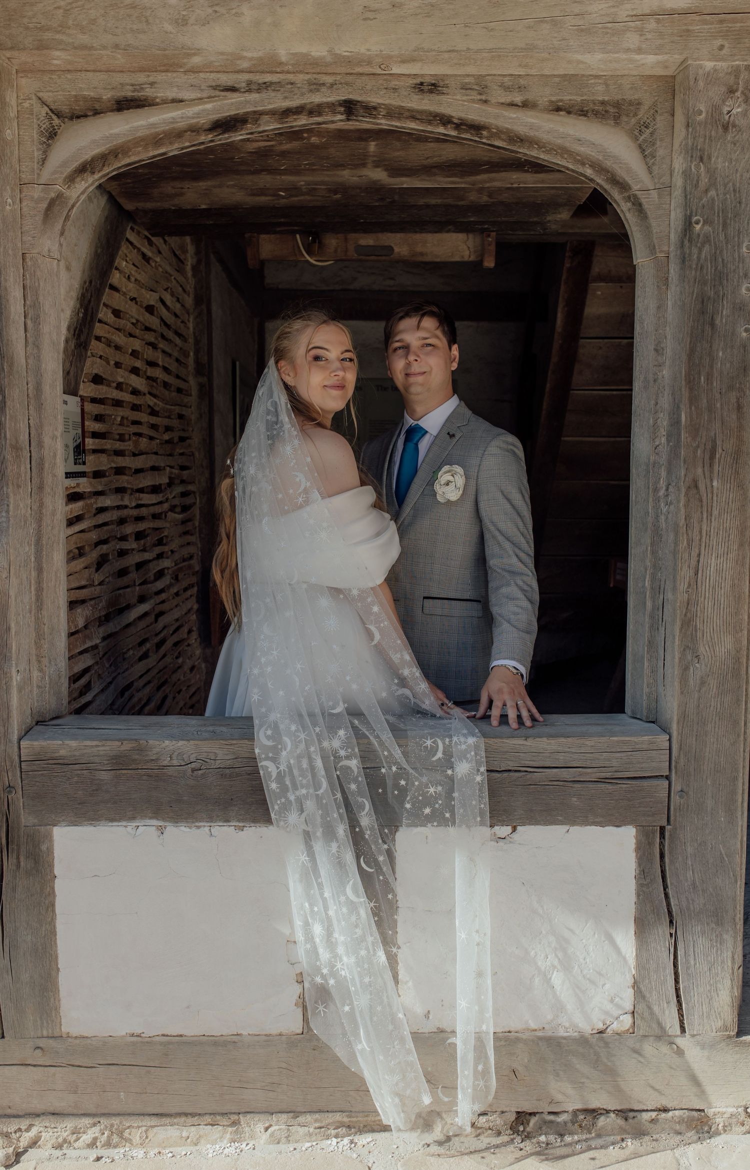 Wedding couple poses together in rustic window frames of historic brick building.