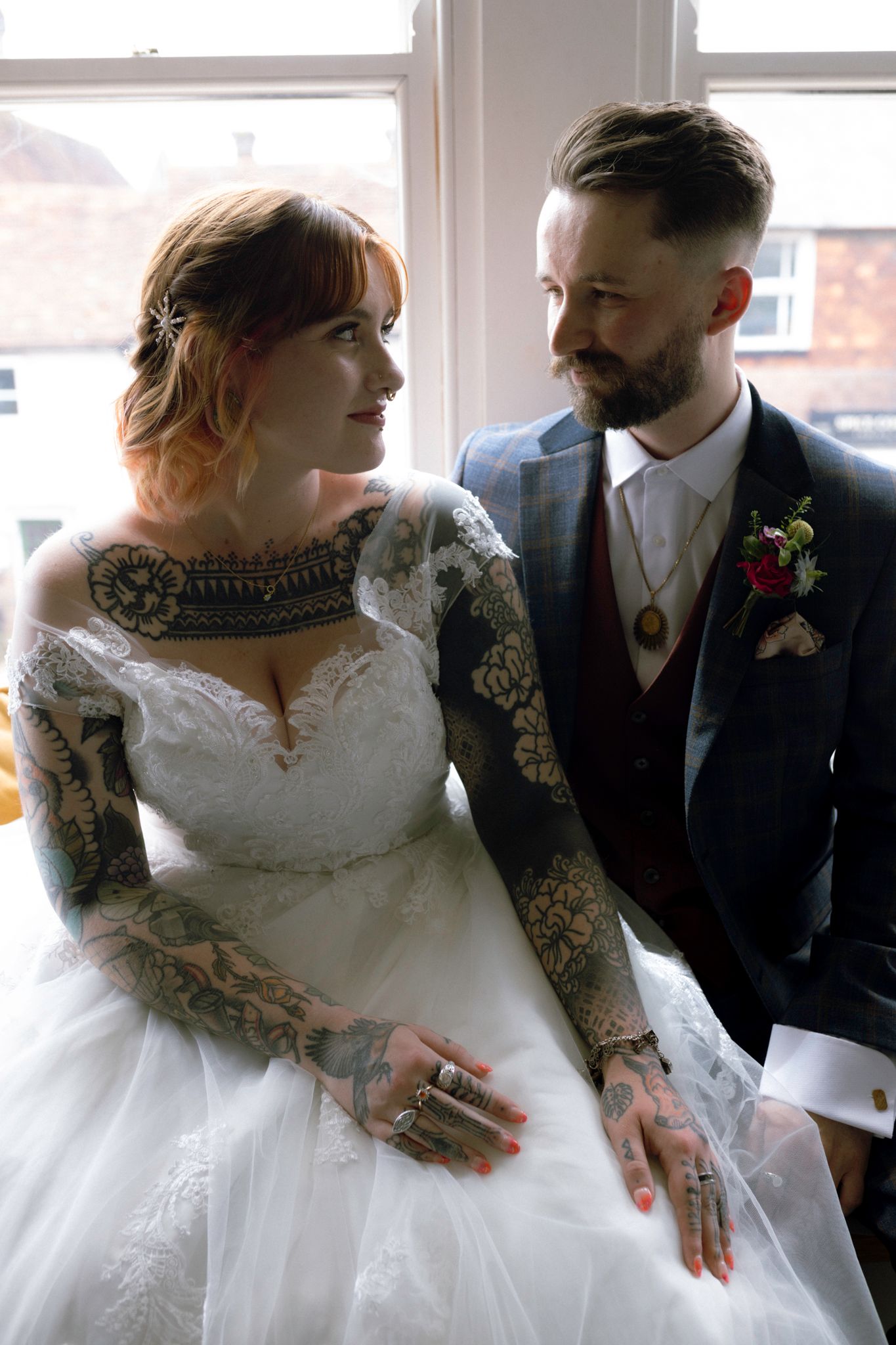 A romantic wedding couple in white dress and dark suit share intimate moments in a sunlit room.