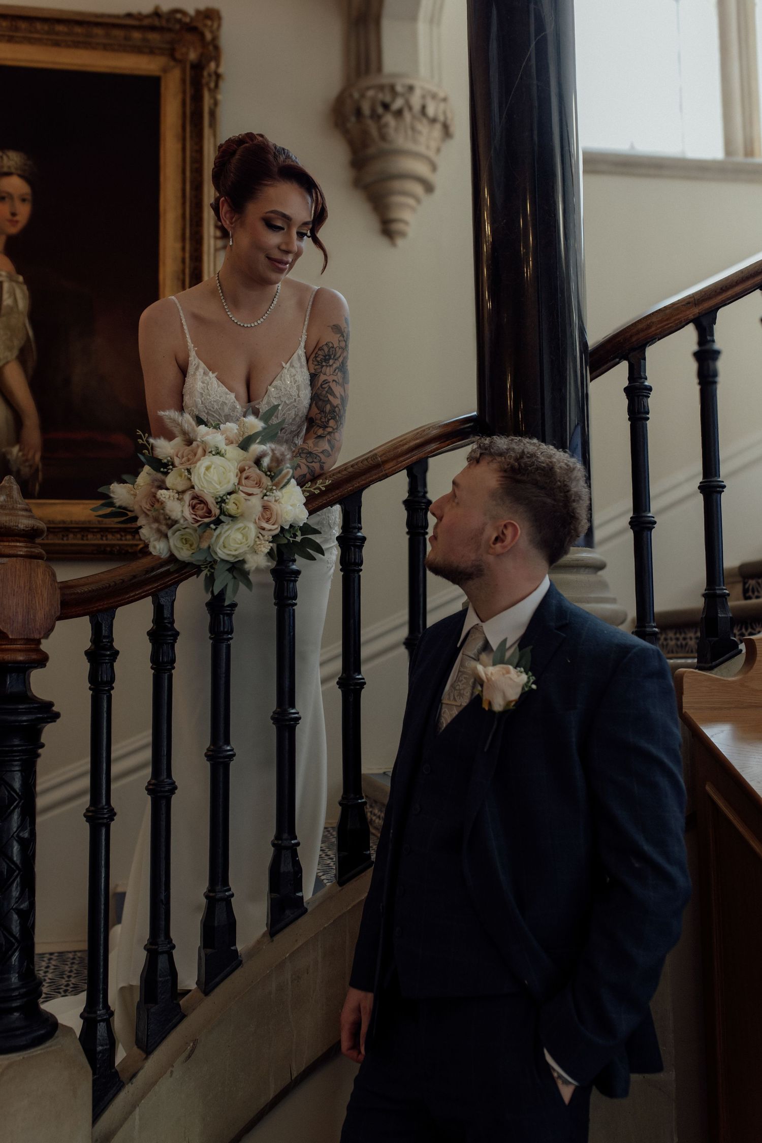 Bride and groom looking at each other on staircase .