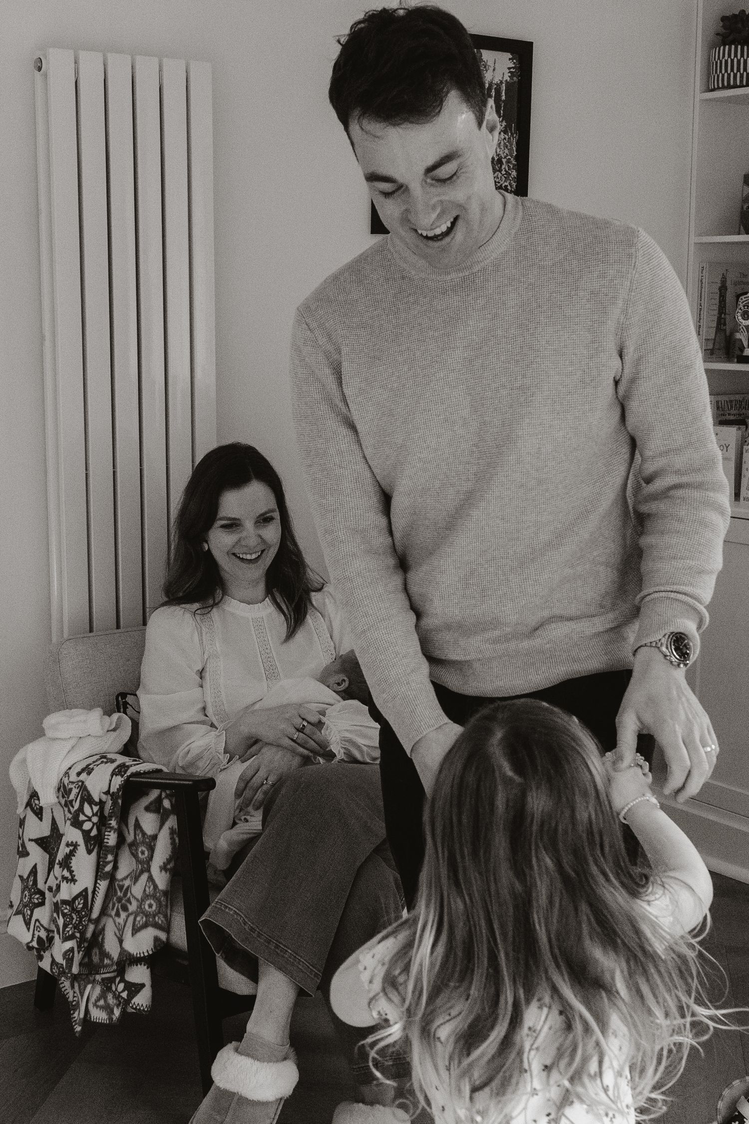 A series of black and white photos showing tender moments between a parent and child sitting together indoors.
