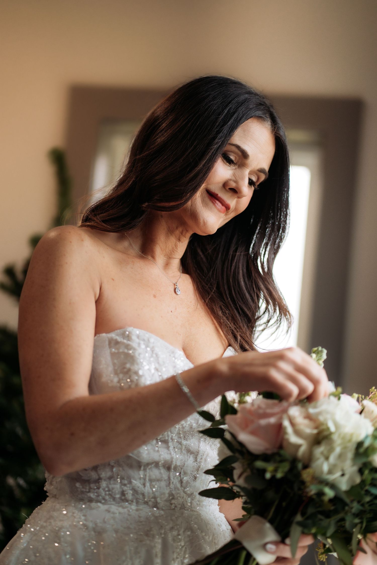 “Bride smiling while adjusting her bouquet, half‑body portrait in natural light.”
