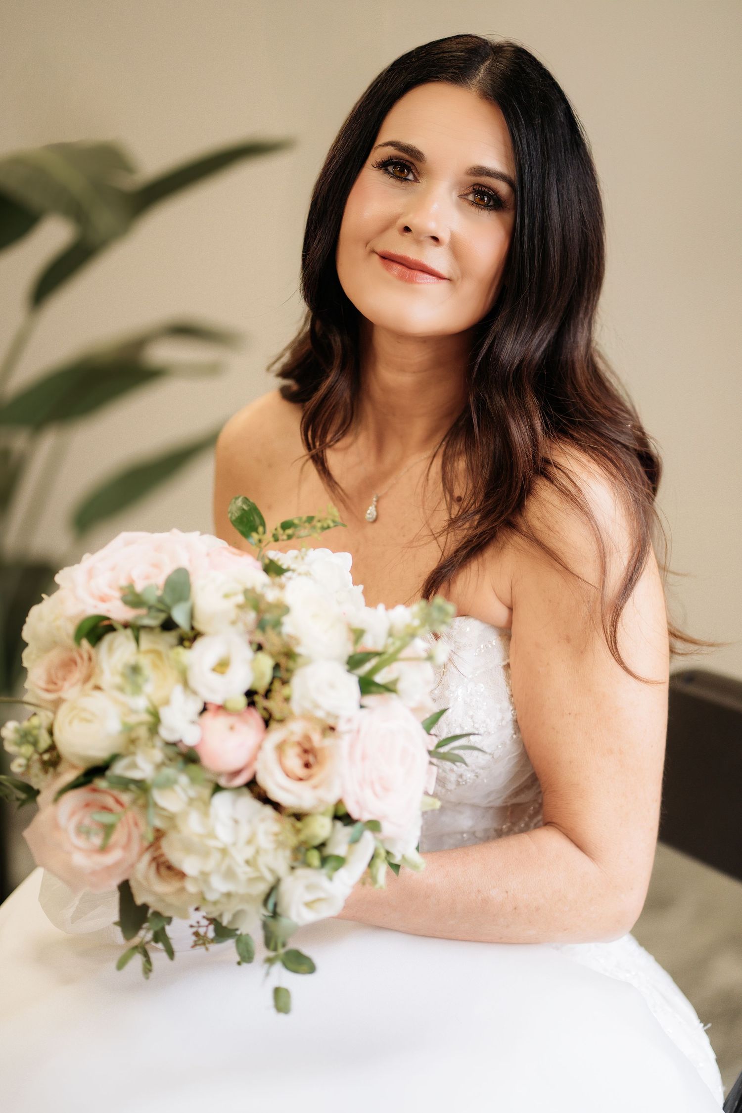 “Half‑body portrait of a bride sitting and holding her bouquet, captured in soft natural light.”