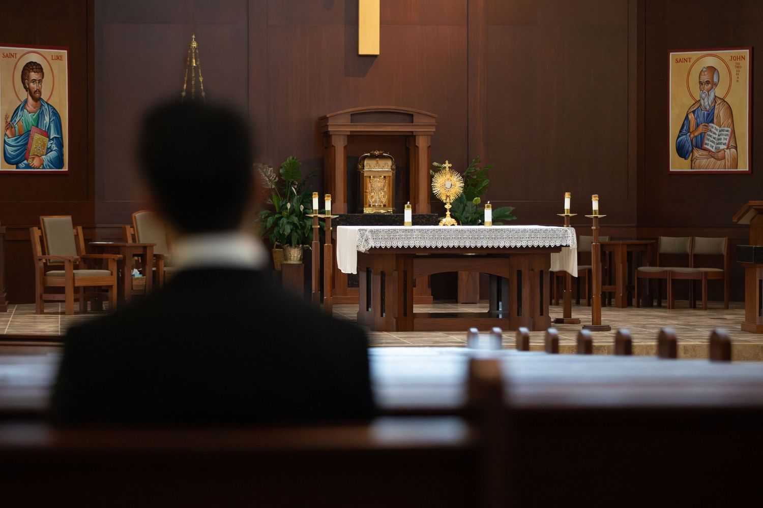 A view of a church altar with religious icons, candles, and white cloth in a dimly lit sanctuary.