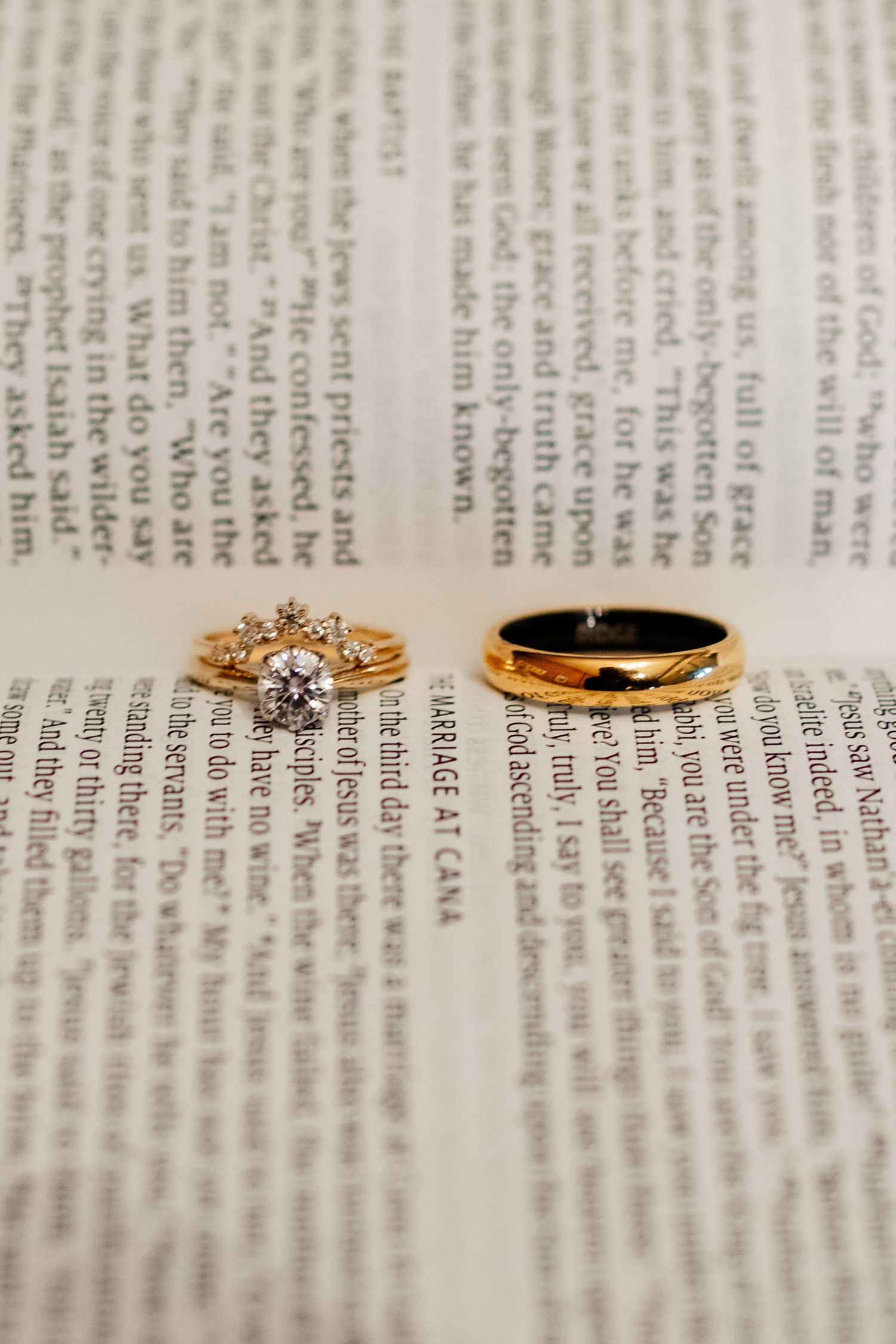 Four elegant gold and diamond rings arranged in a row on an open book page with text.