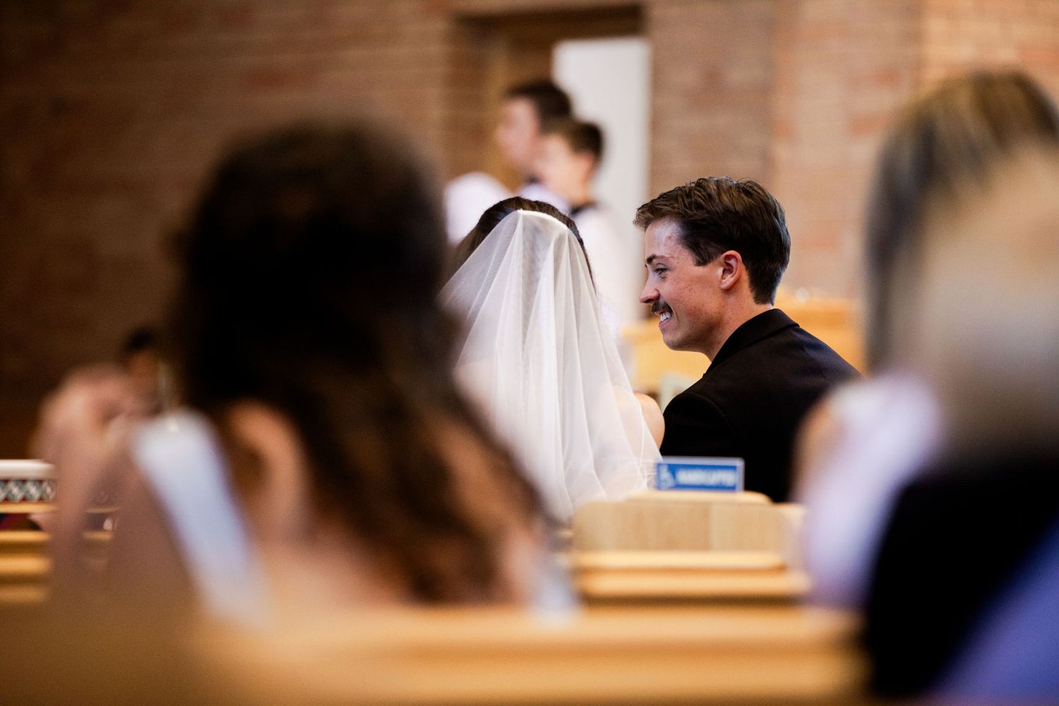 An intimate wedding ceremony moment captured in a brick-walled church sanctuary.