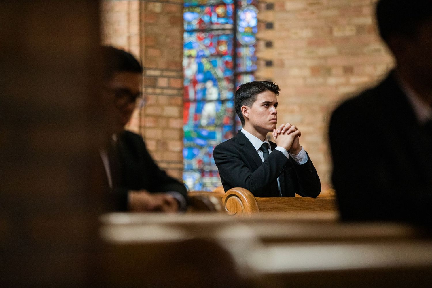 A groom and bride share a joyful moment during their wedding ceremony inside a church with stained glass windows.
