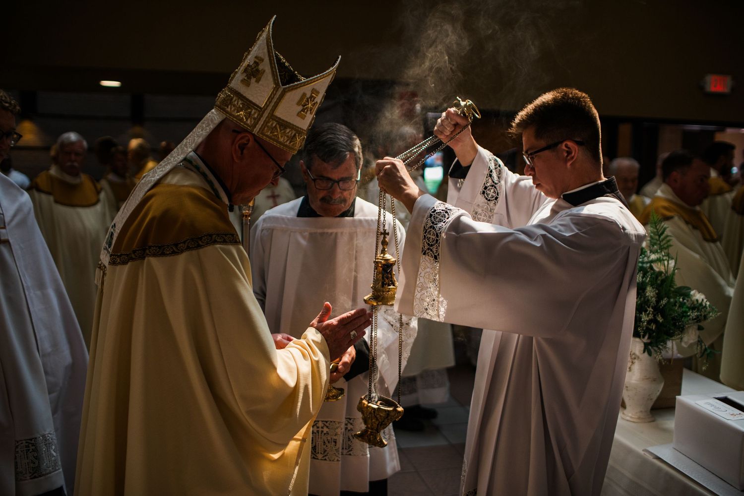 Catholic bishop in ceremonial vestments receives incense during a solemn Mass liturgical ceremony with clergy.