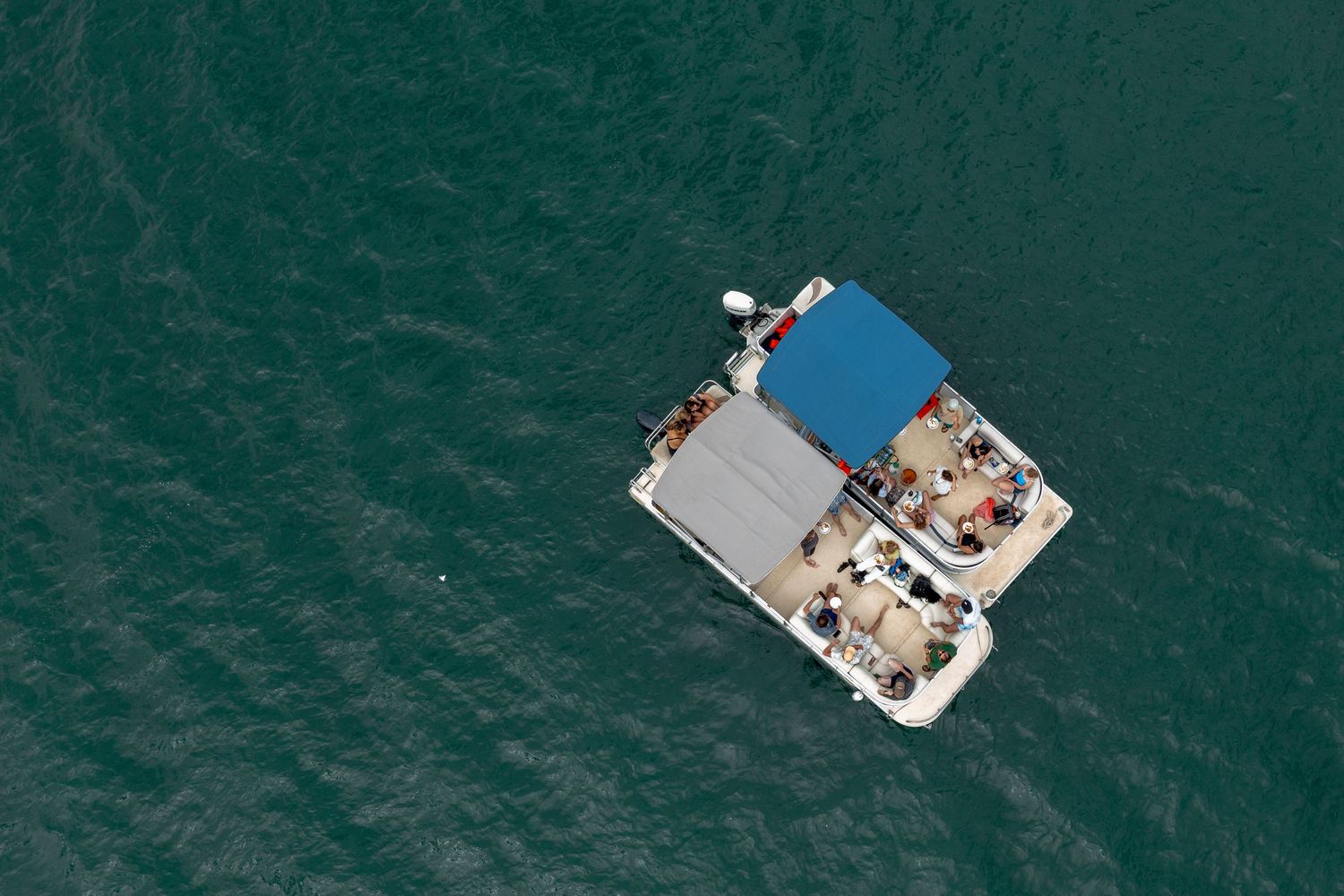 Aerial view of a boat with snorkelers swimming in clear turquoise waters near a tropical reef.