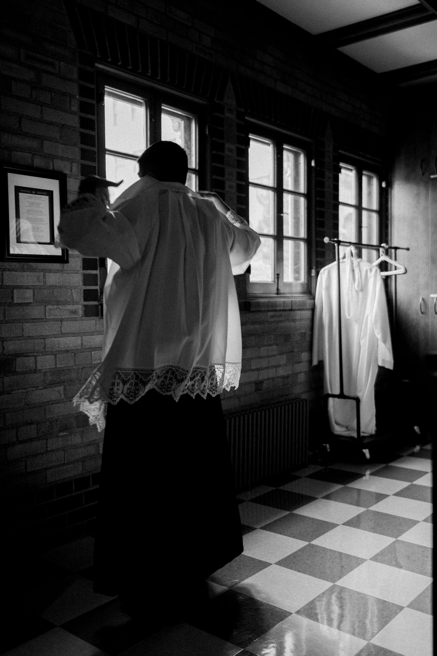 Eerie black and white scene of floating white sheets in a dark room with checkered floor and window light.