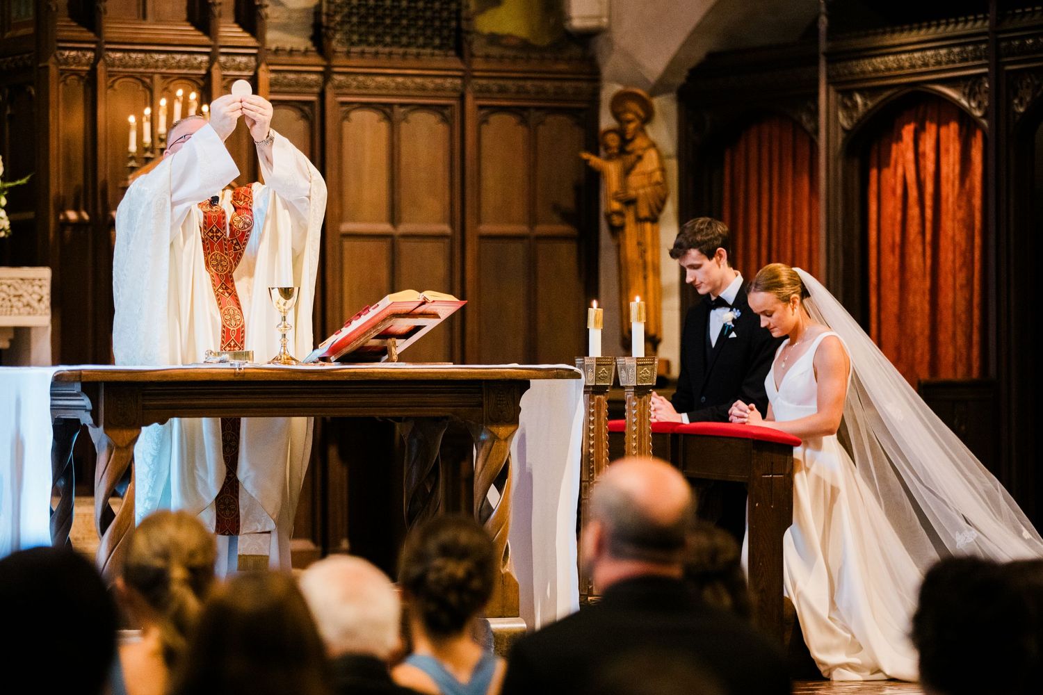 Bride and groom signing wedding registry at church altar during elegant traditional ceremony.