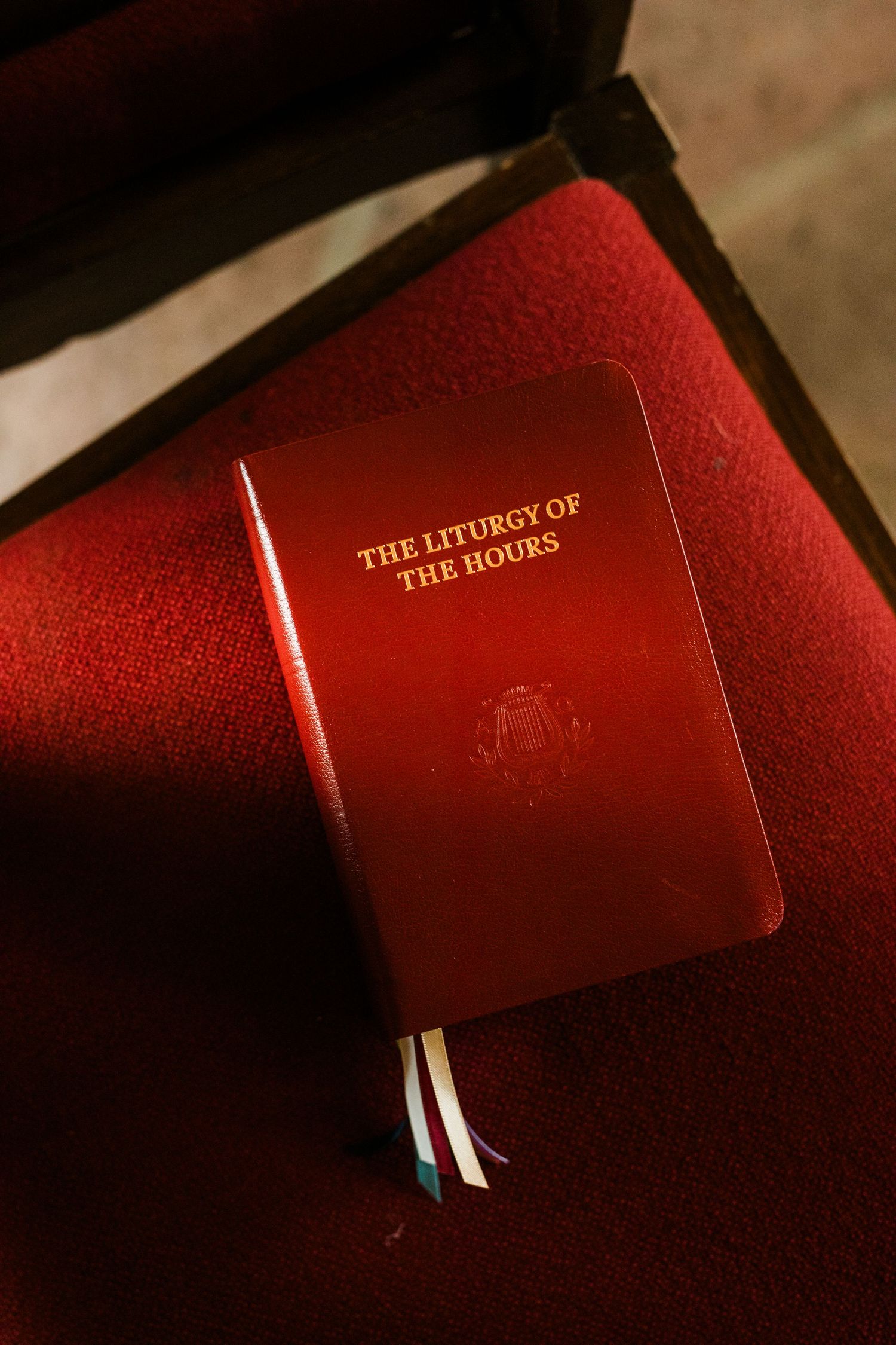 Red leather-bound Liturgy of the Hours book with gold text resting on a red velvet chair.