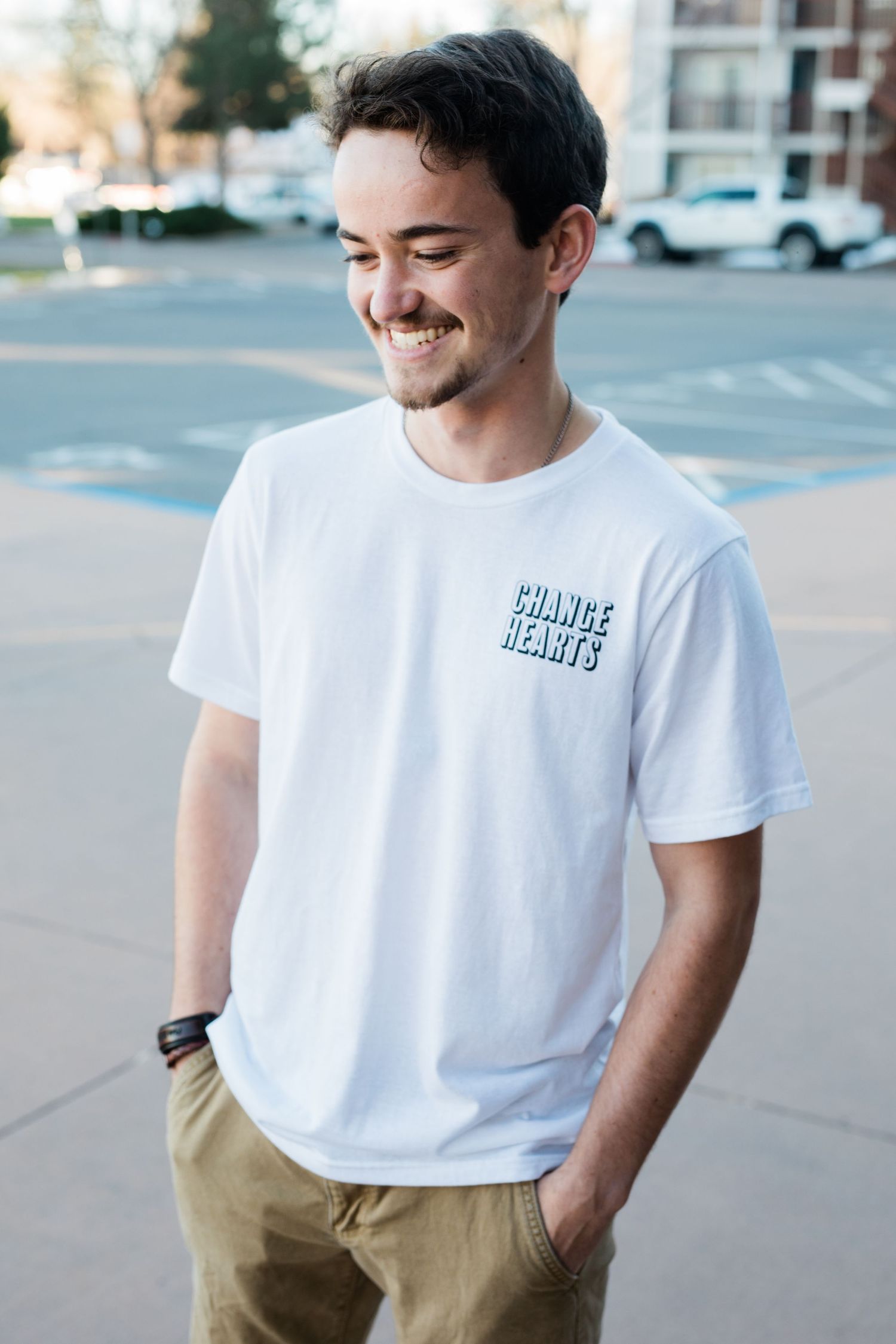 Casual white t-shirt style photographed in outdoor urban setting.