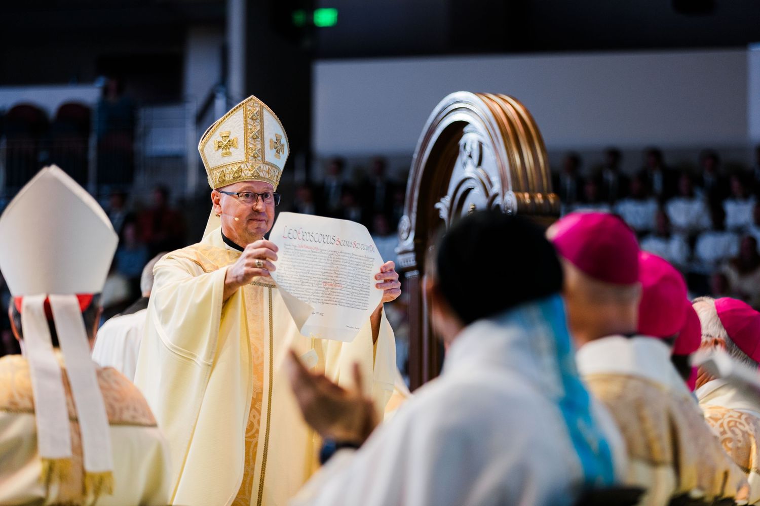 Religious clergy in ceremonial robes conducting a formal service in a large venue.