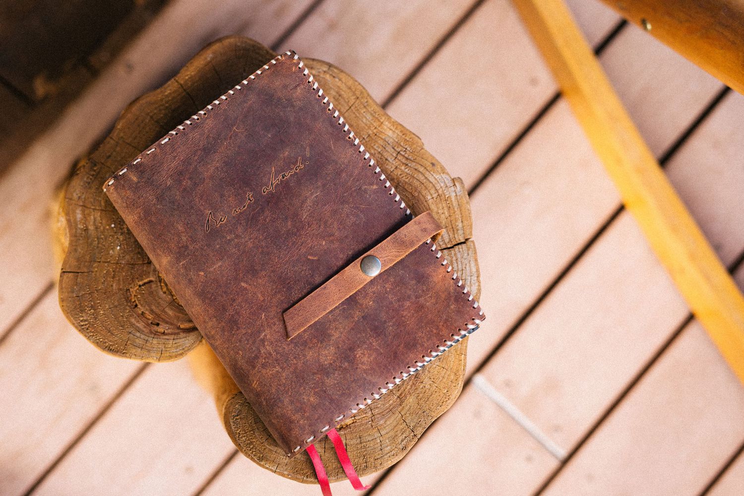 Old brown leather wallet with fading and distress marks against a wooden background.