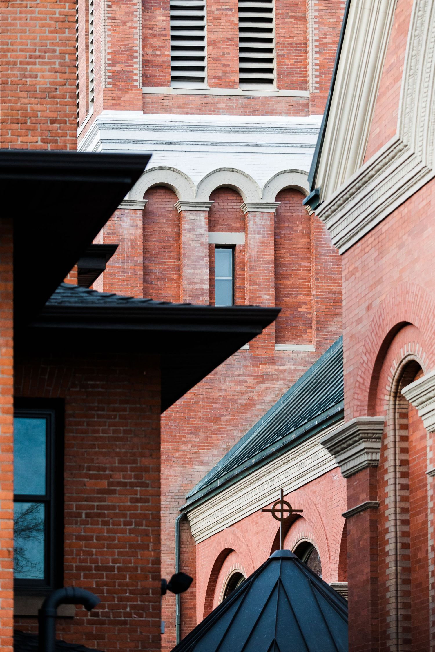 Architectural detail of red brick church with arched windows and decorative stonework.