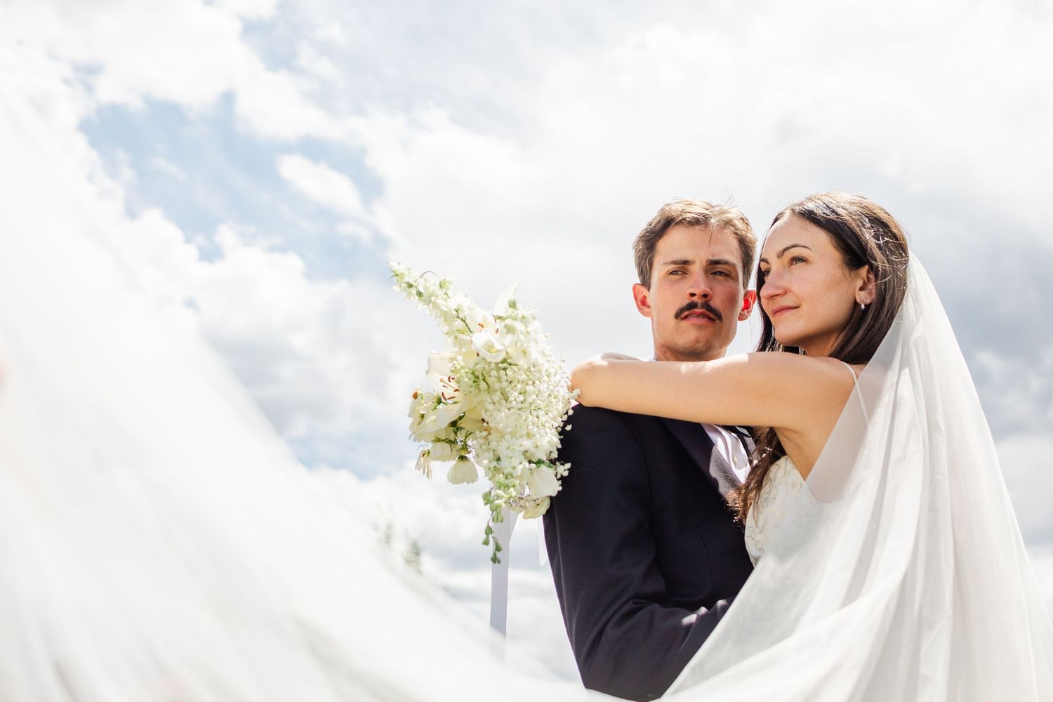 A series of four romantic wedding photos showing tender moments between the couple against a bright outdoor backdrop.