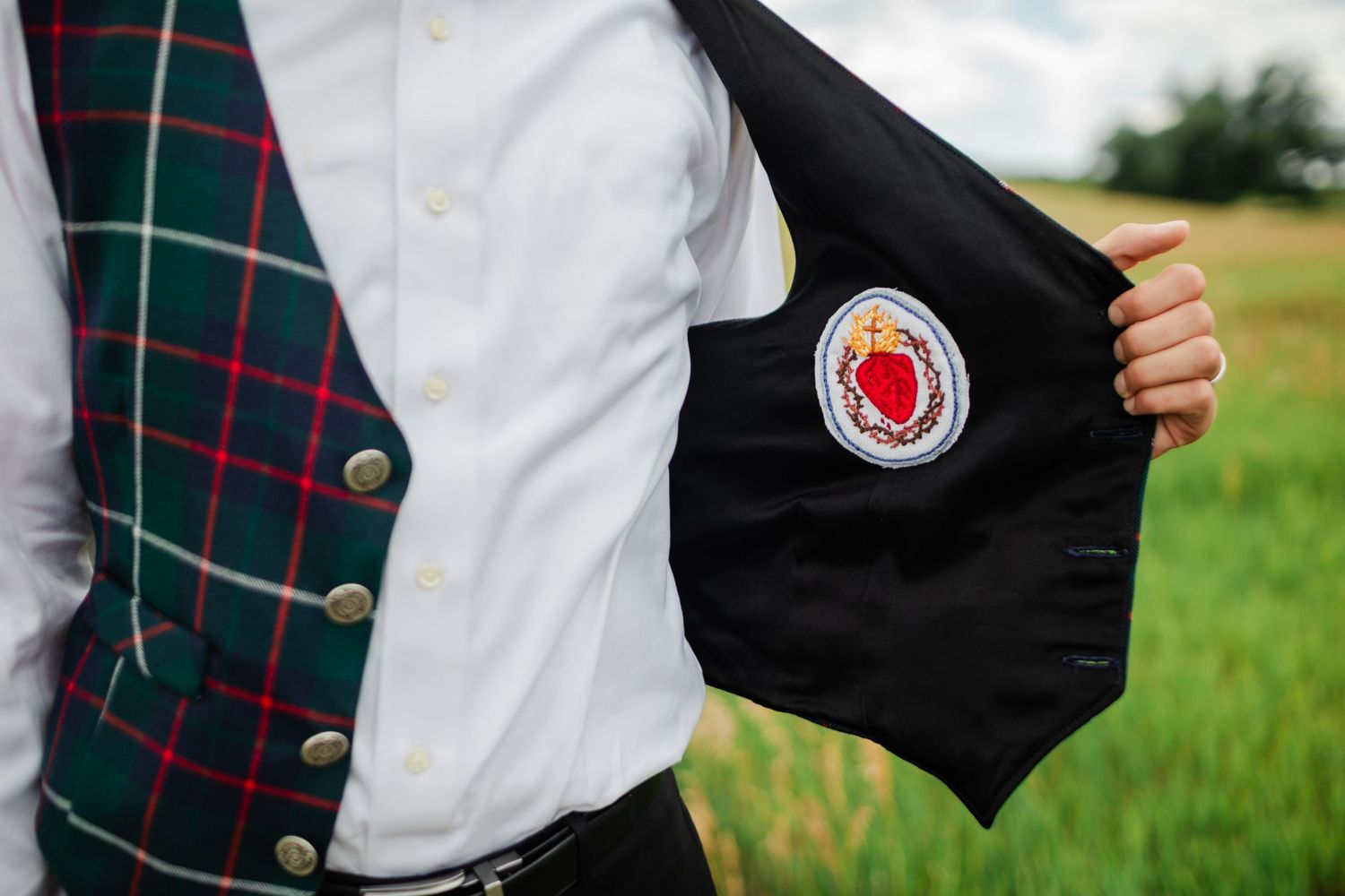 Students in plaid uniforms and black vests stand in a row outdoors during a school event.