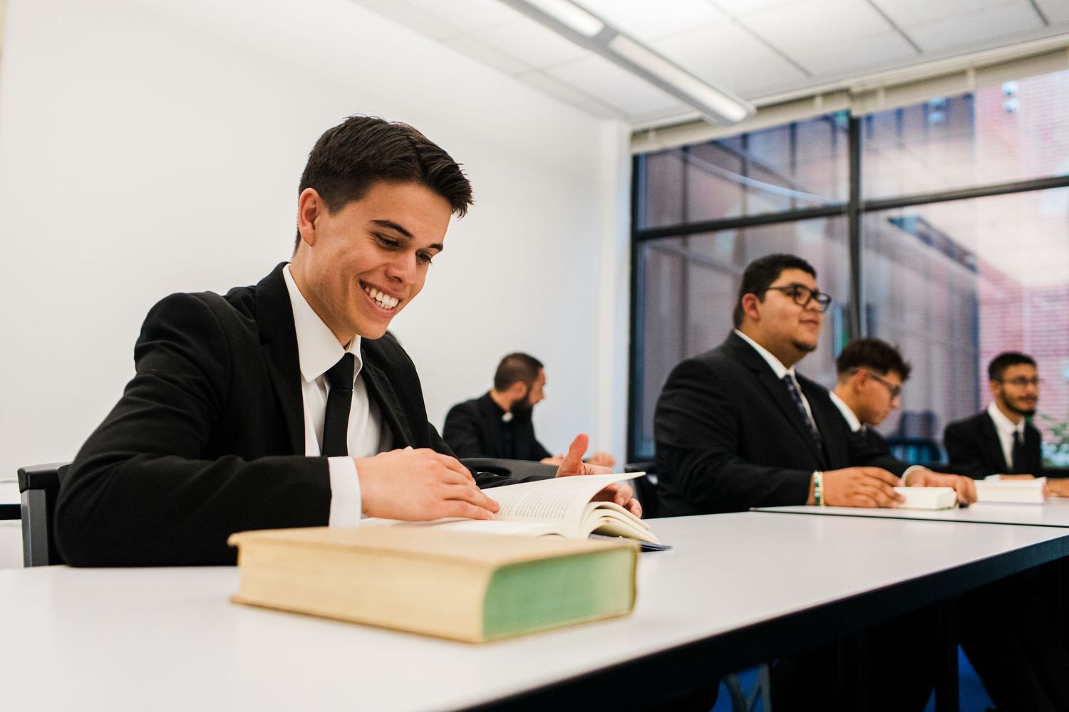Students in formal attire working at desks in a modern classroom setting.