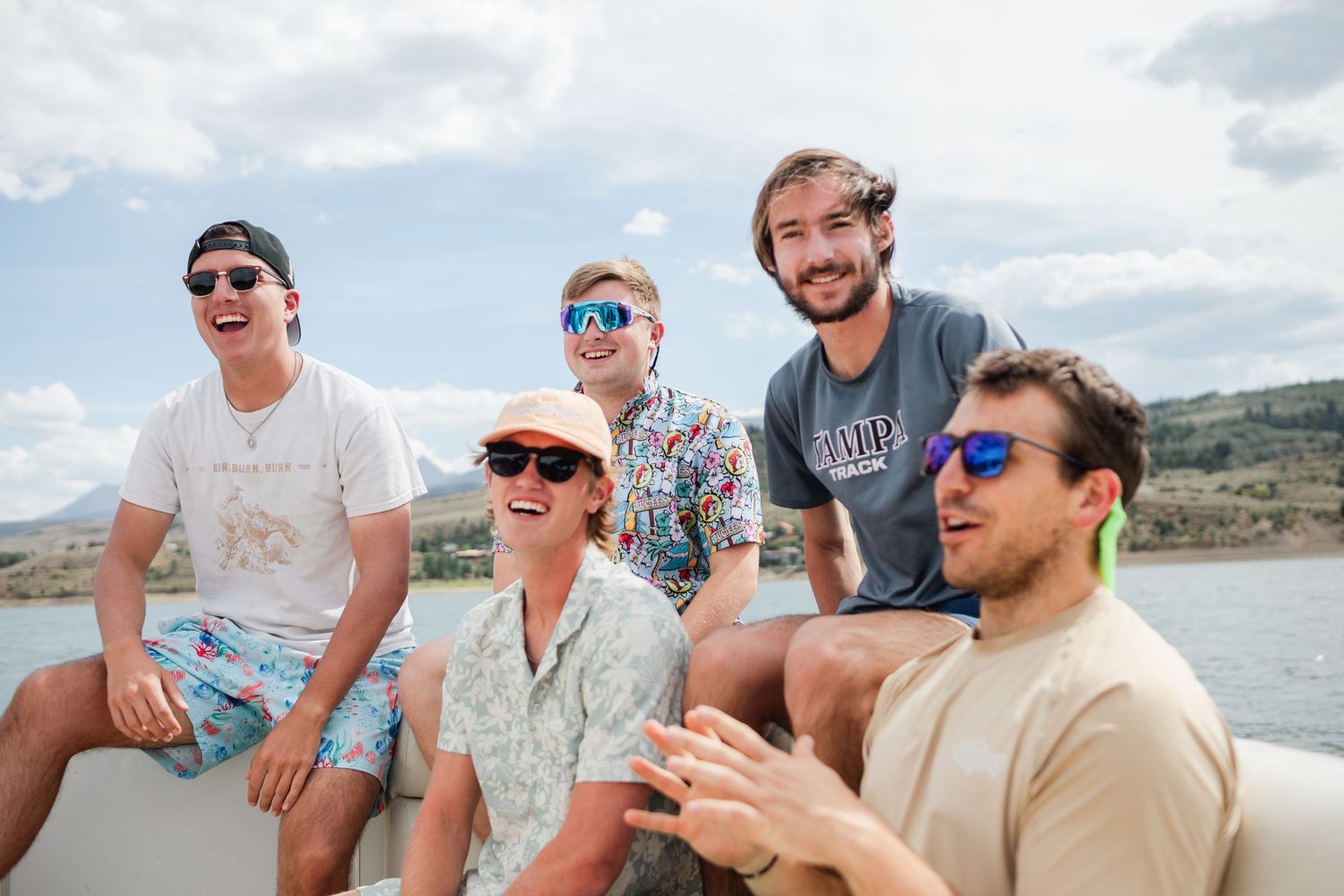 A group of friends laughing and enjoying themselves while sitting together on a boat near the shoreline.