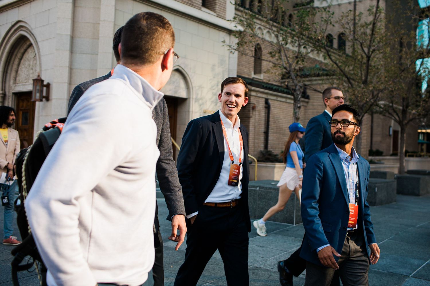 Business professionals with lanyards networking outdoors at a conference event.