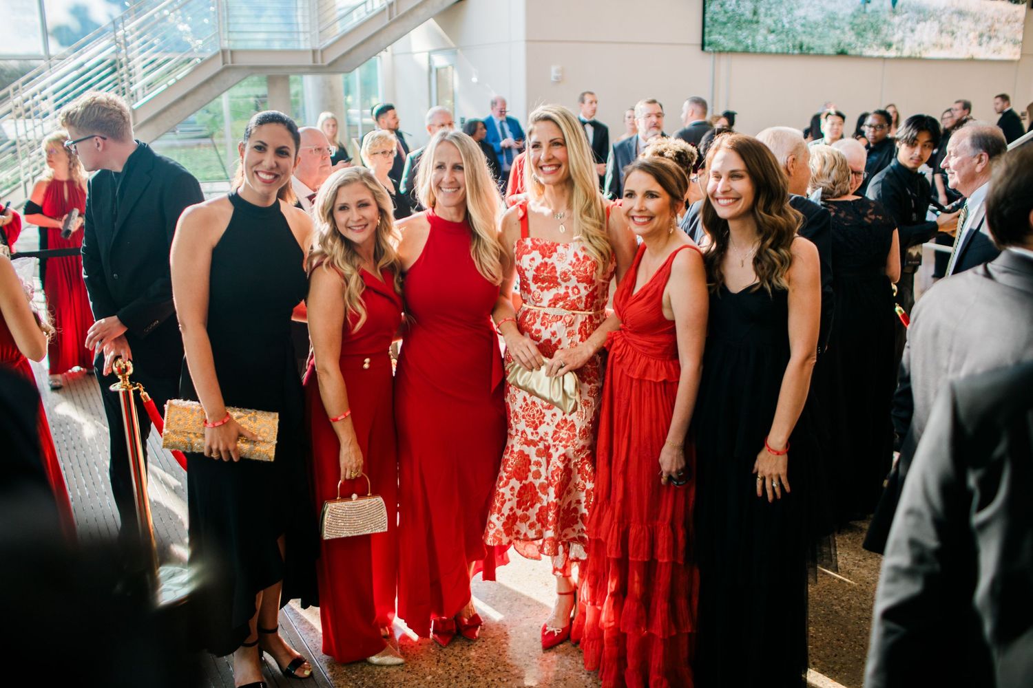 Wedding guests in red and black attire dance together on a crowded dance floor at an elegant reception celebration.