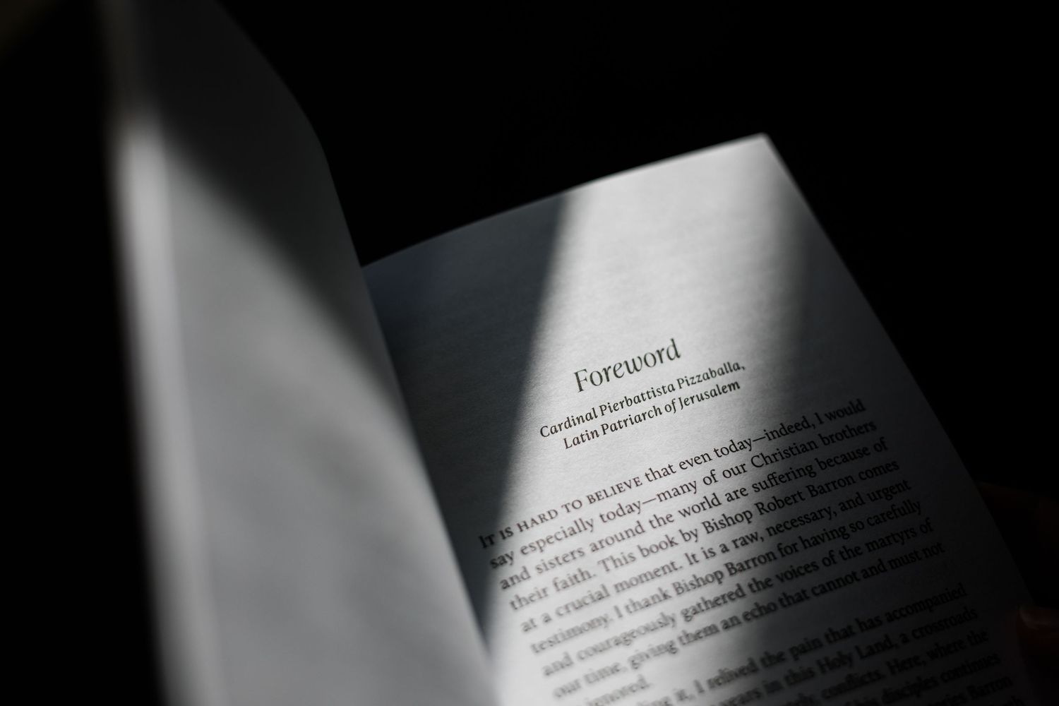 Open book showing a Foreword page, illuminated by dramatic light against a dark background.