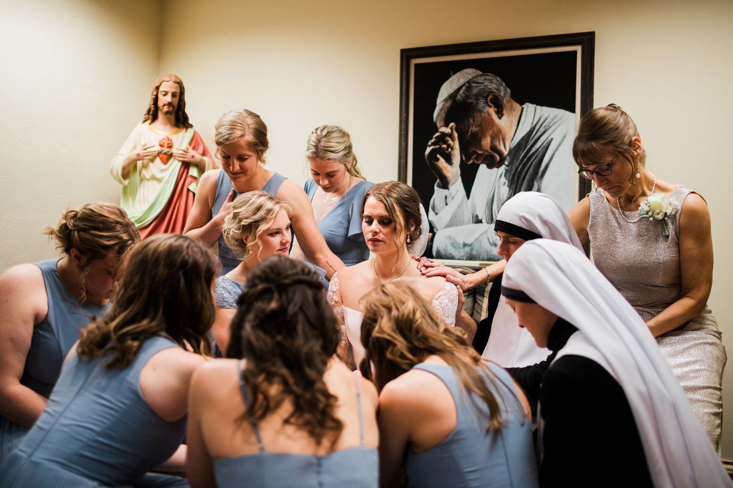 Group in blue dresses gathered in prayer during religious ceremony.