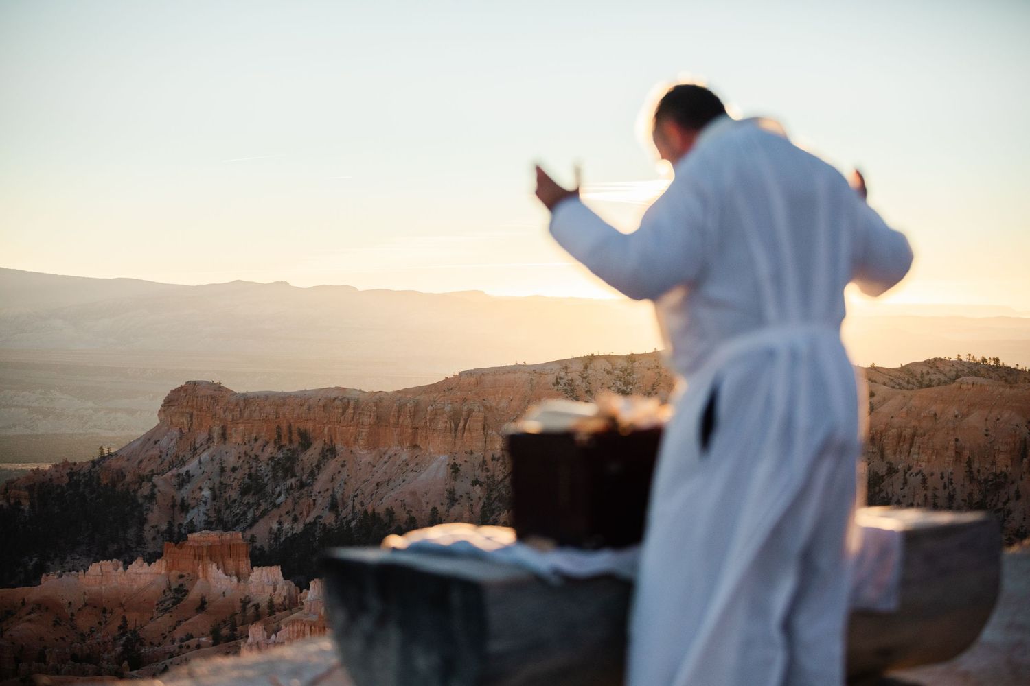 Panoramic view of Bryce Canyon's red rock formations and hoodoos at sunset with a person observing the landscape.