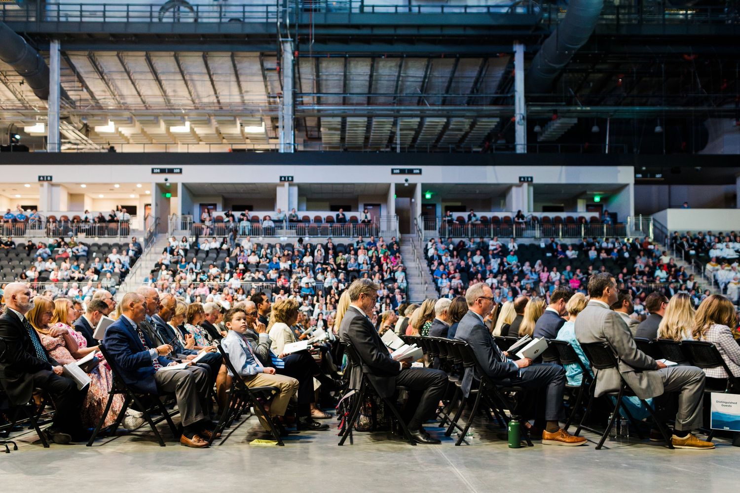Wide panoramic view of congregation seated in rows at indoor religious gathering.