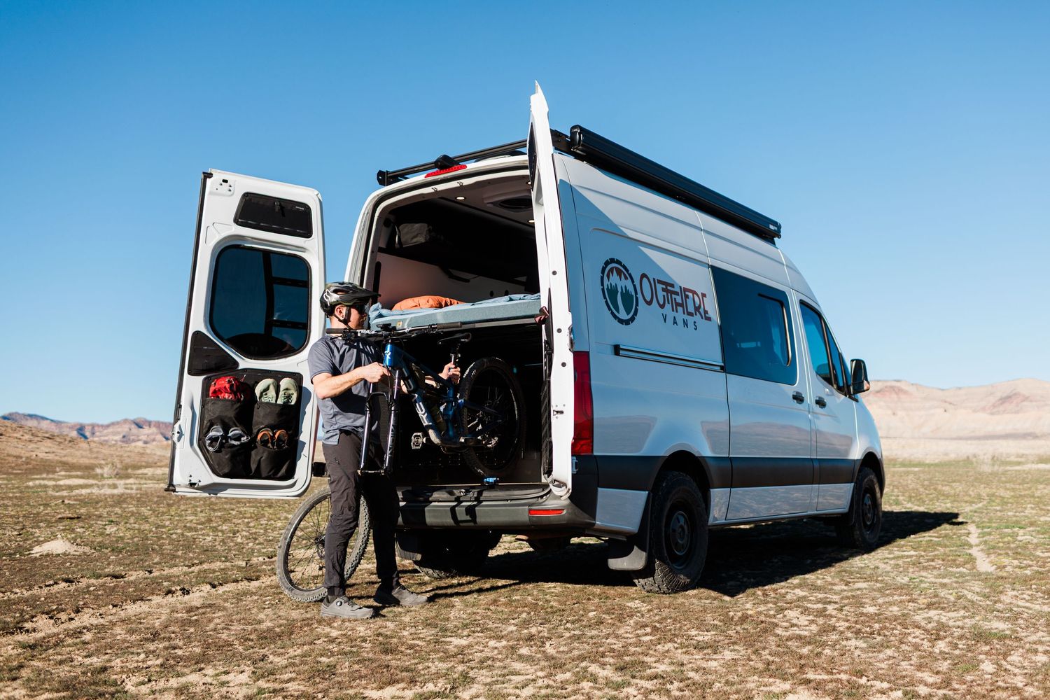Multiple white vans parked in a desert setting during a product photoshoot.