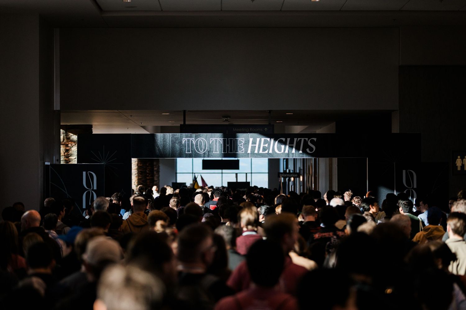 A dark auditorium filled with silhouettes of people seated in rows during a presentation or performance.