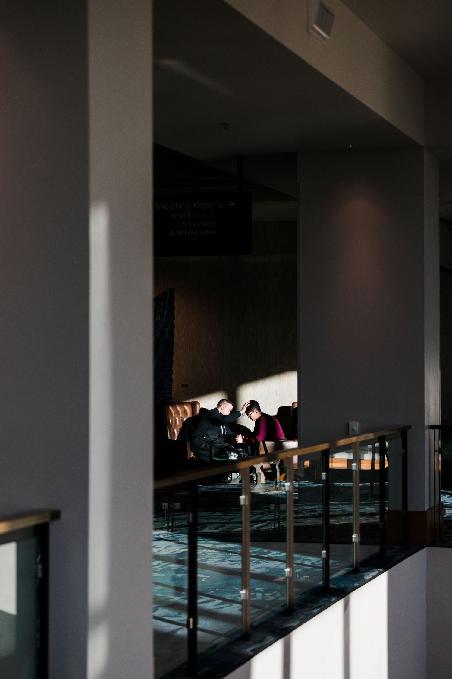 A dimly lit interior space with people sitting in a modern architectural setting with dramatic lighting.