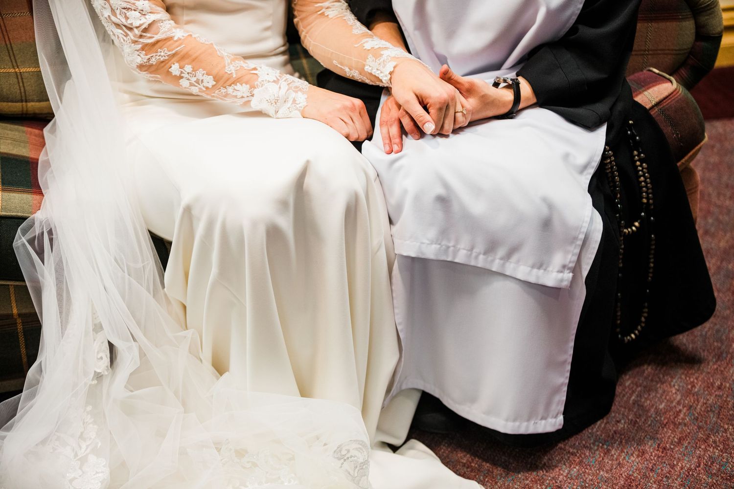 Hands folded in white robes during a sacred ceremony.