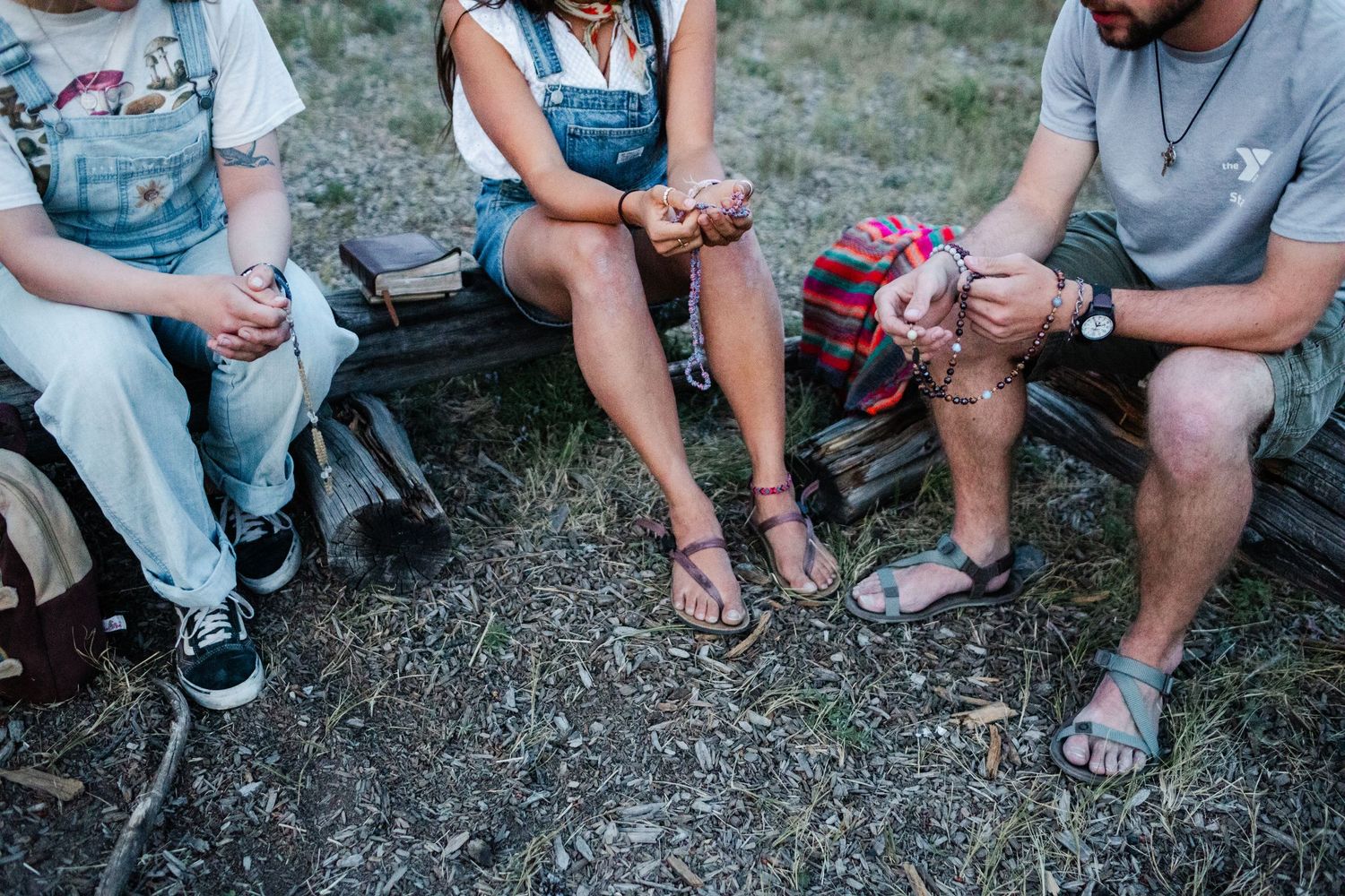 Group sitting together on grass wearing casual clothing and sneakers at outdoor gathering.