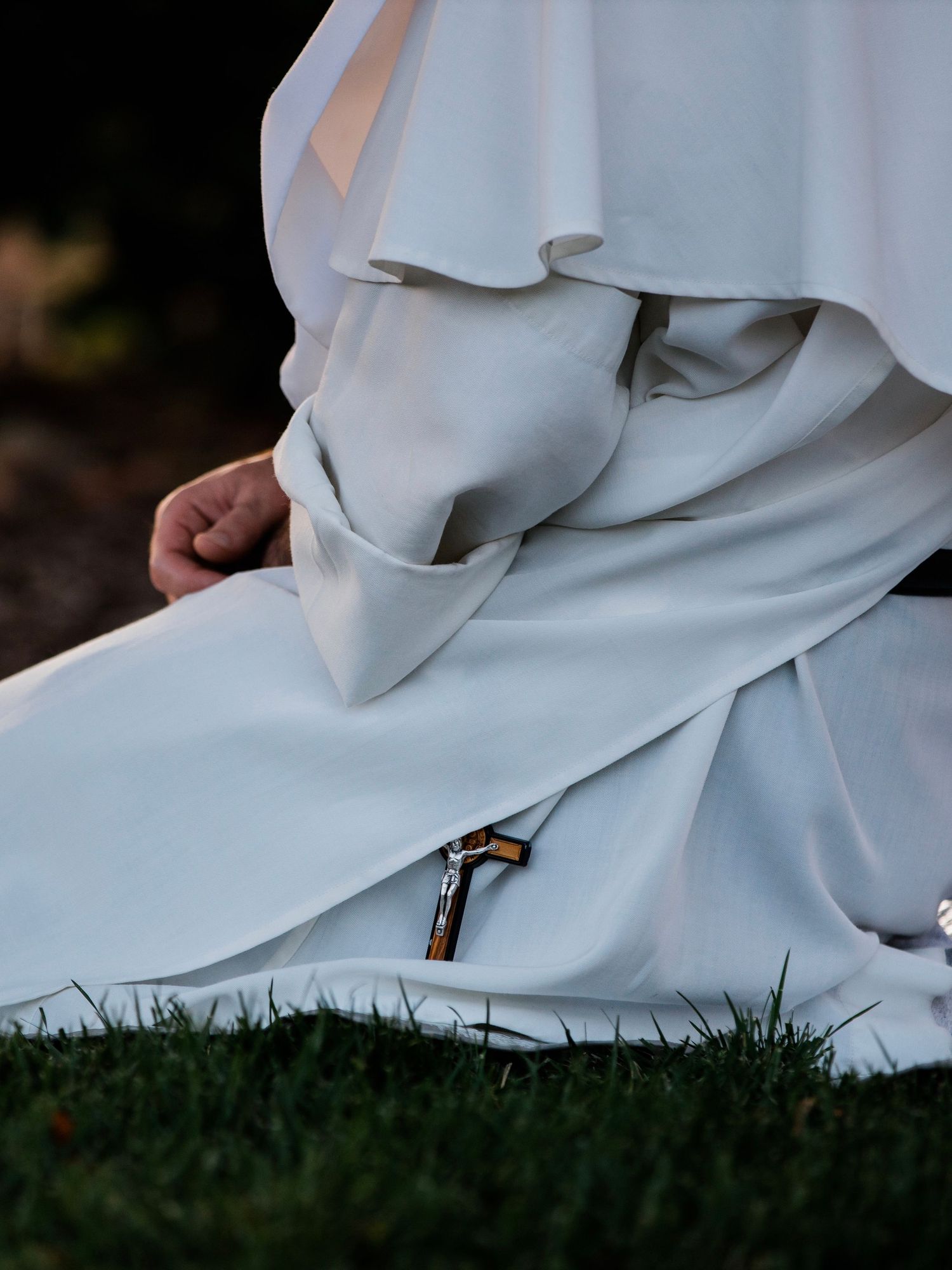 White robes flowing over green grass in a natural setting.