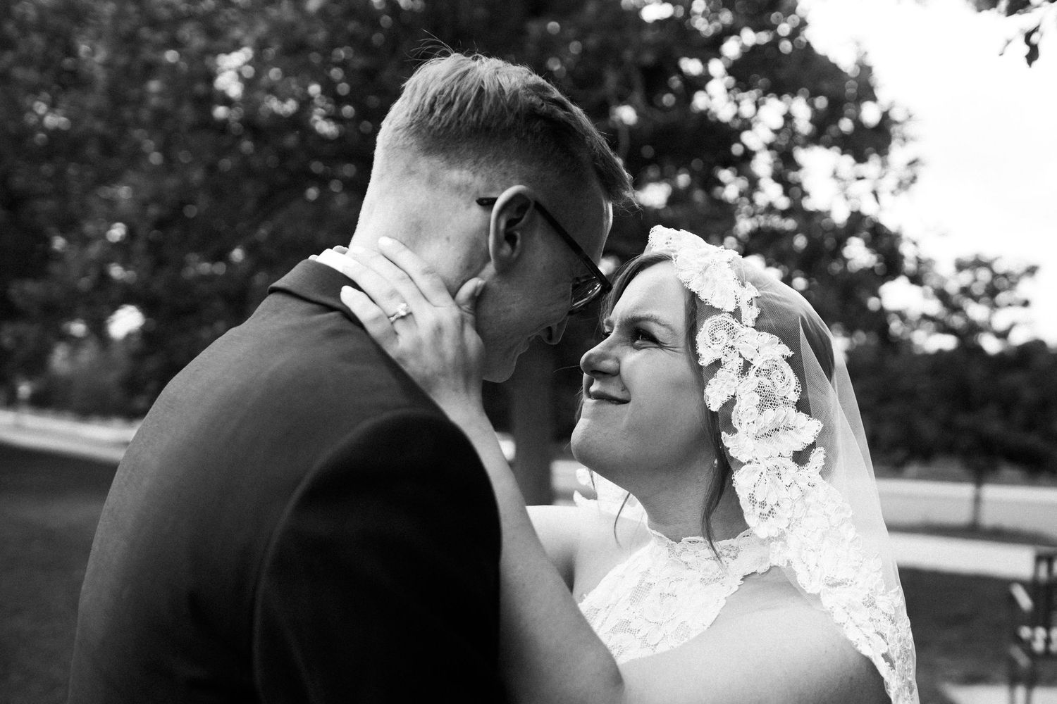 Black and white photo of bride and groom gazing at each other outdoors on wedding day.