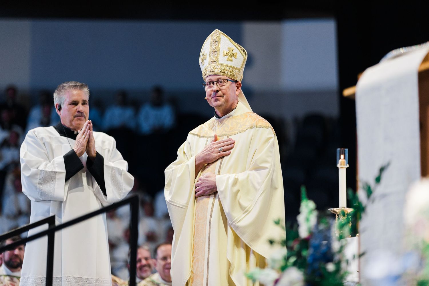 Religious clergy members in white robes and gold vestments stand together during a ceremonial service.