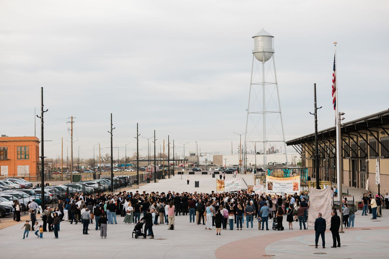 A panoramic view of crowds gathered at a winter festival on a snowy pier with a lighthouse and water tower visible.