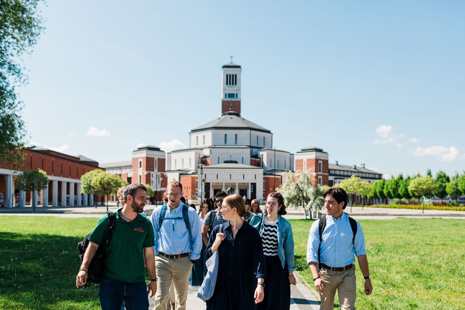 Students walking on a sunny college campus with a historic brick rotunda building in the background.