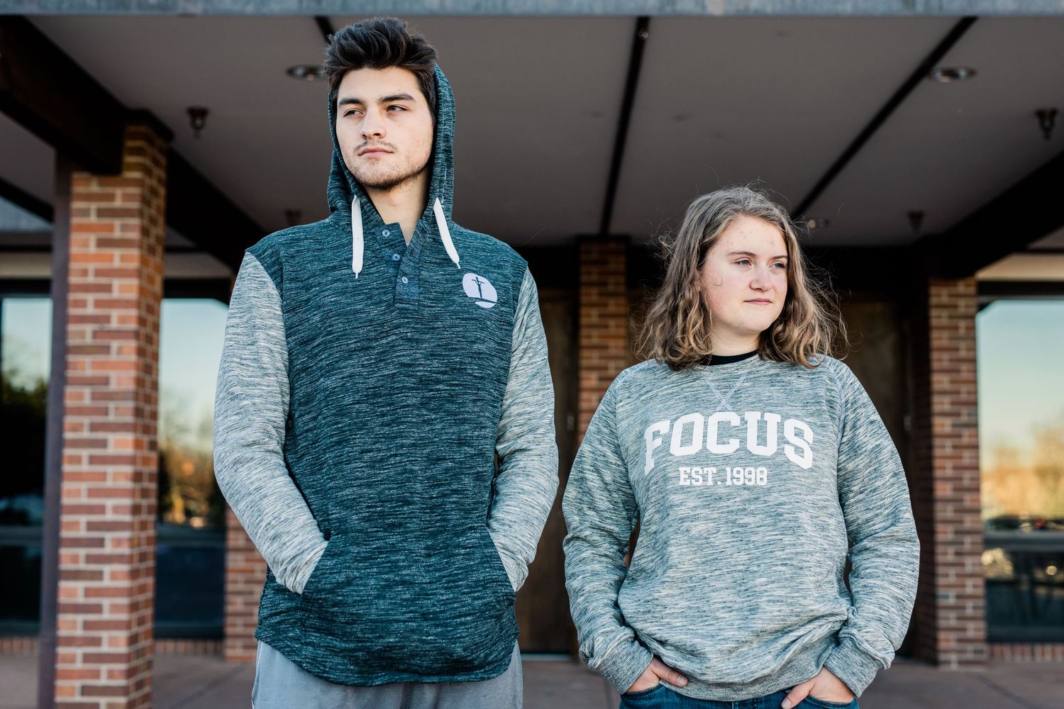 Athletic figures in heather gray and teal workout apparel stand against indoor brick walls.