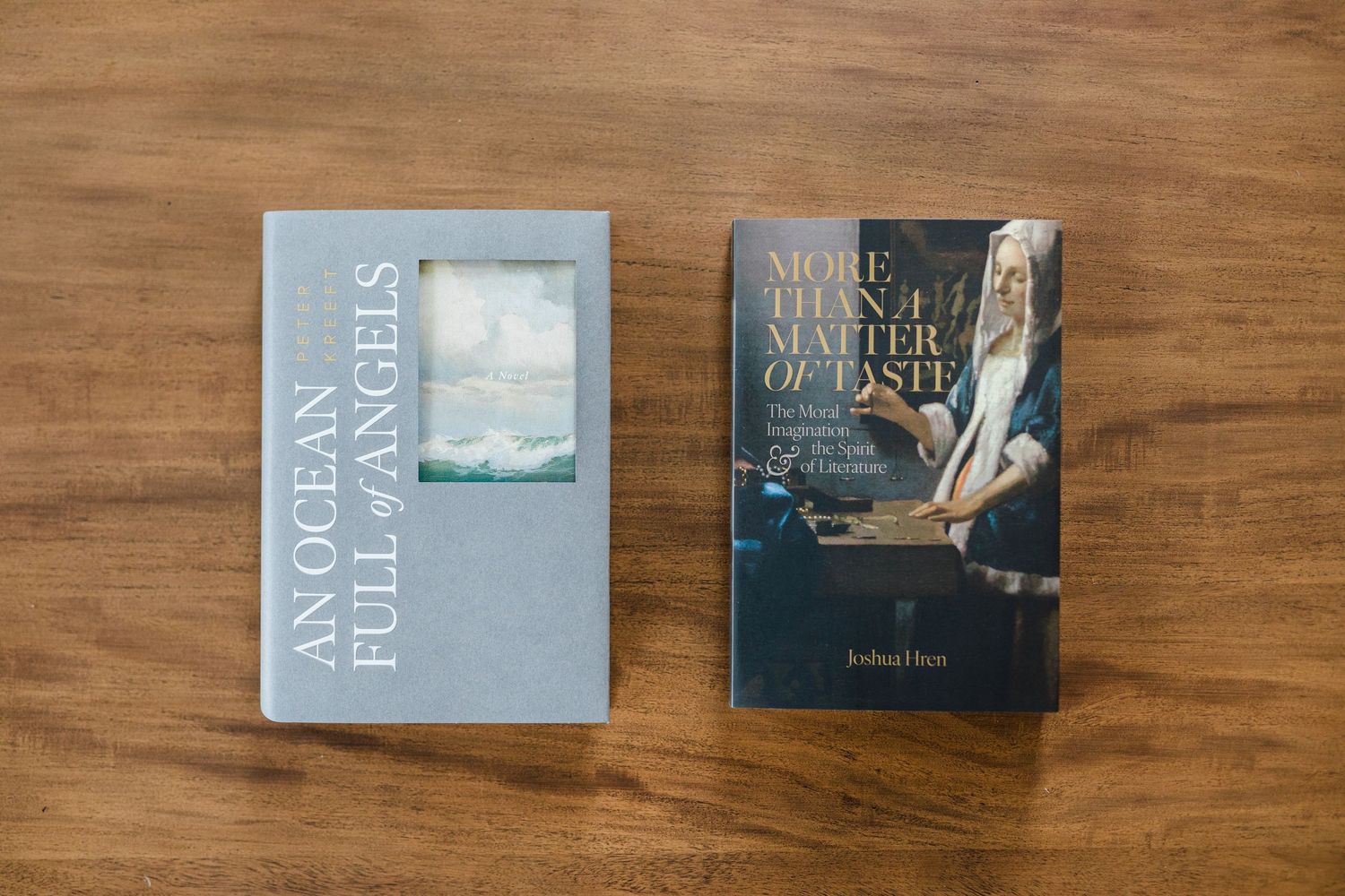 Two Catholic books 'An Ocean Full of Angels' and 'More Than a Matter of Taste' on wooden surface.
